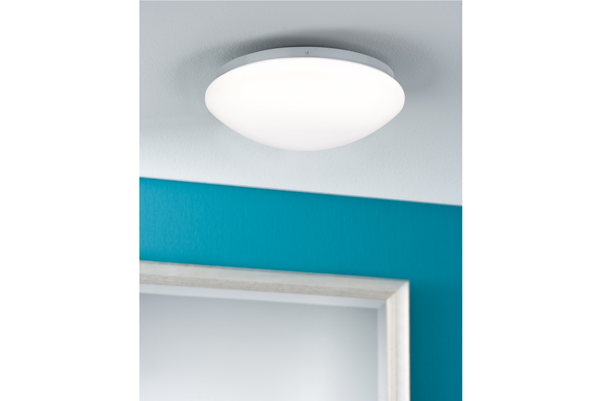 Eine weiße Deckenlampe mit einer blauen Wand und einer Tür mit weißem Rahmen.