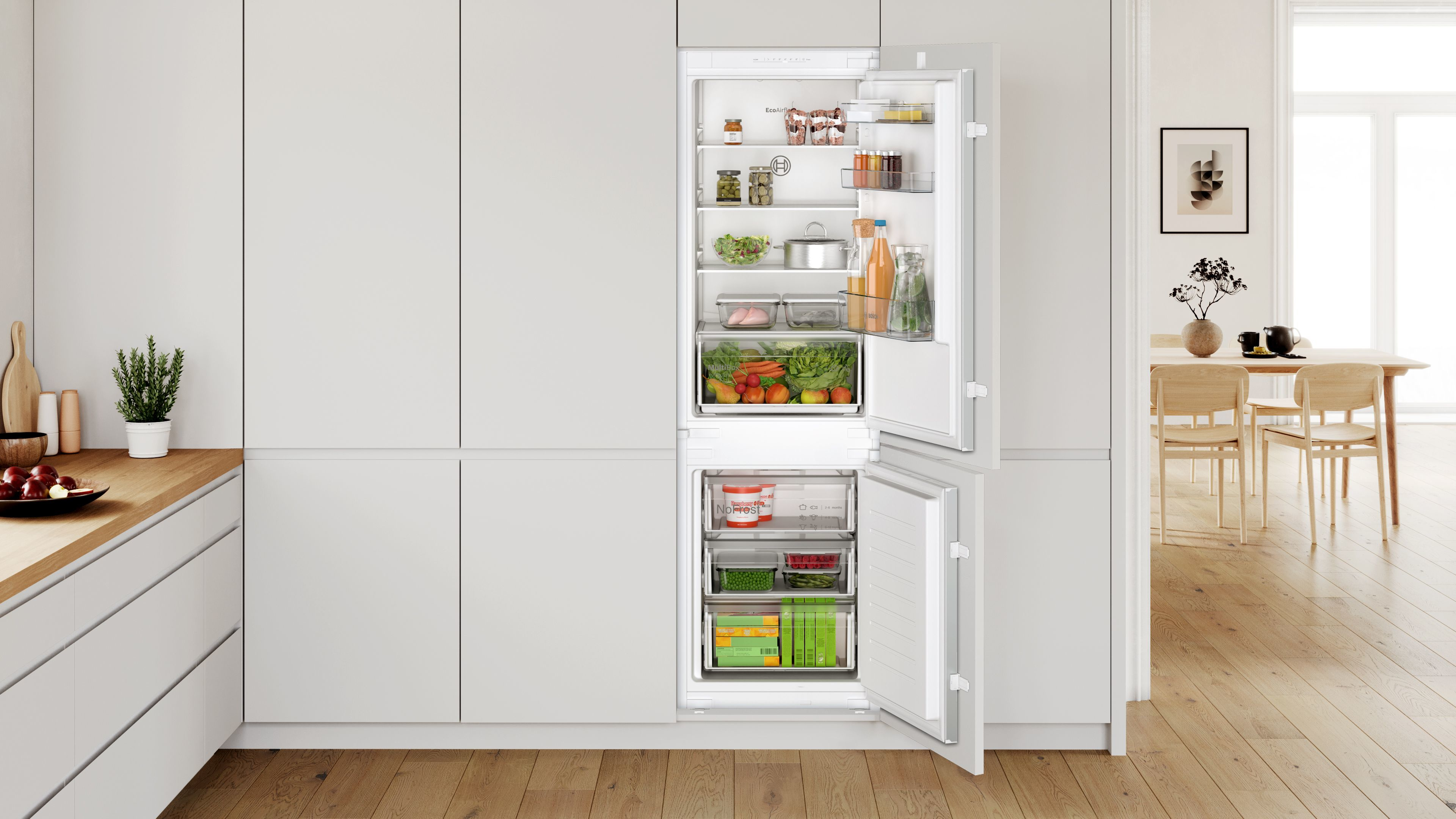 Ein weißer Kühlschrank mit offenen Türen, gefüllt mit Lebensmitteln.