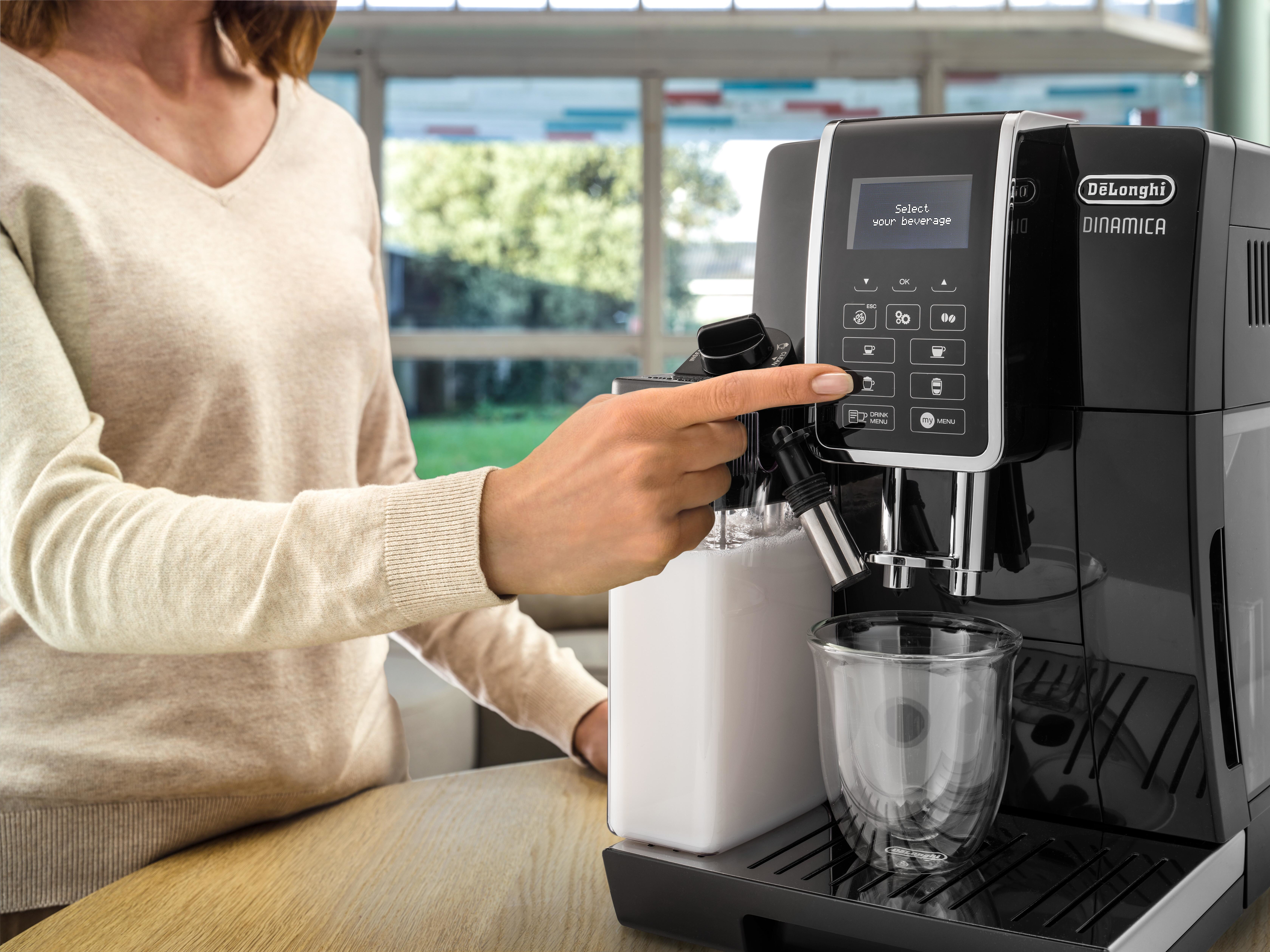Frau, die eine schwarze Kaffeemaschine mit einem weißen Milchbehälter und einem Glas verwendet.