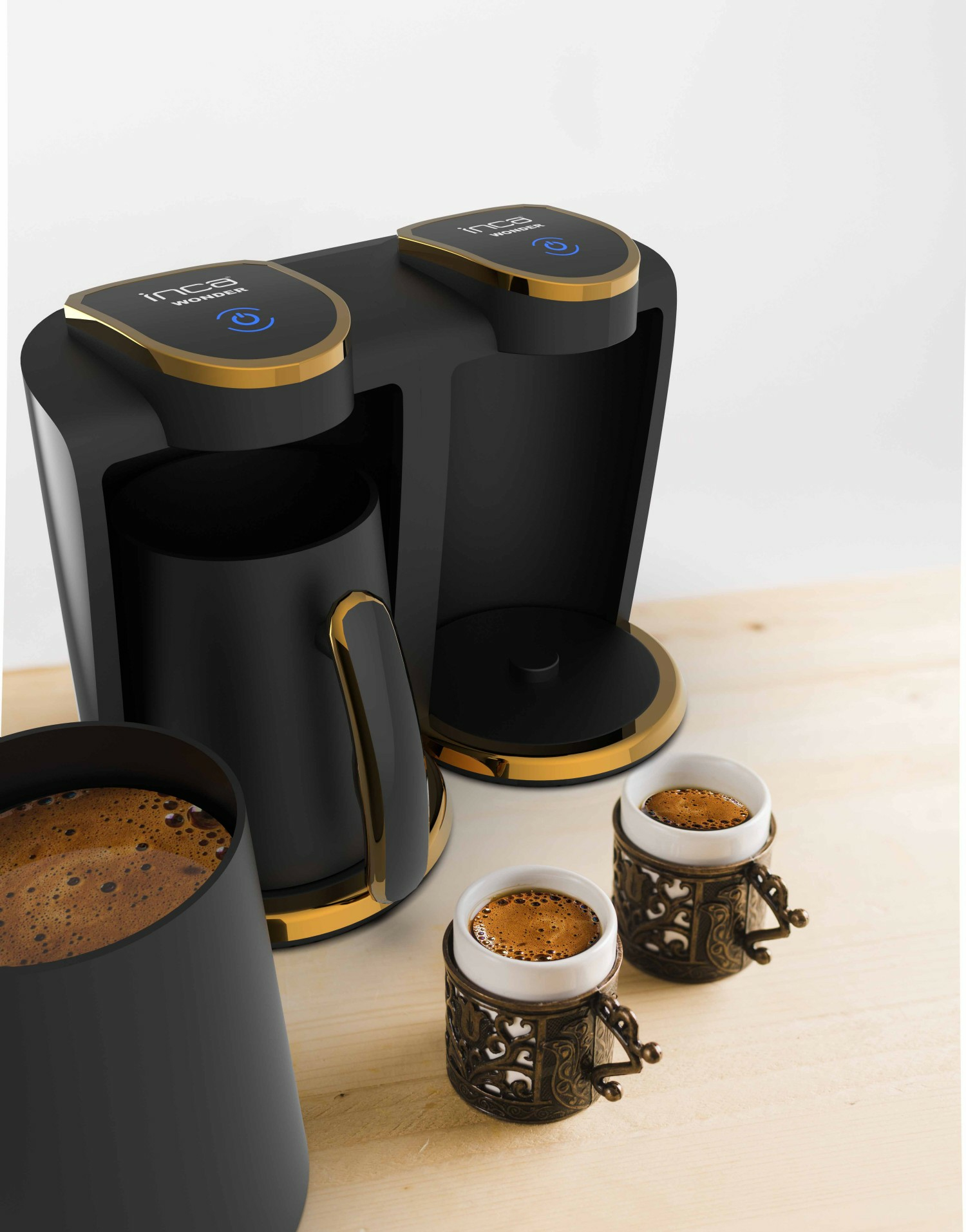 Schwarze Kaffeemaschine mit goldenen Akzenten, zwei Tassen und Kaffee. Modernes Design.