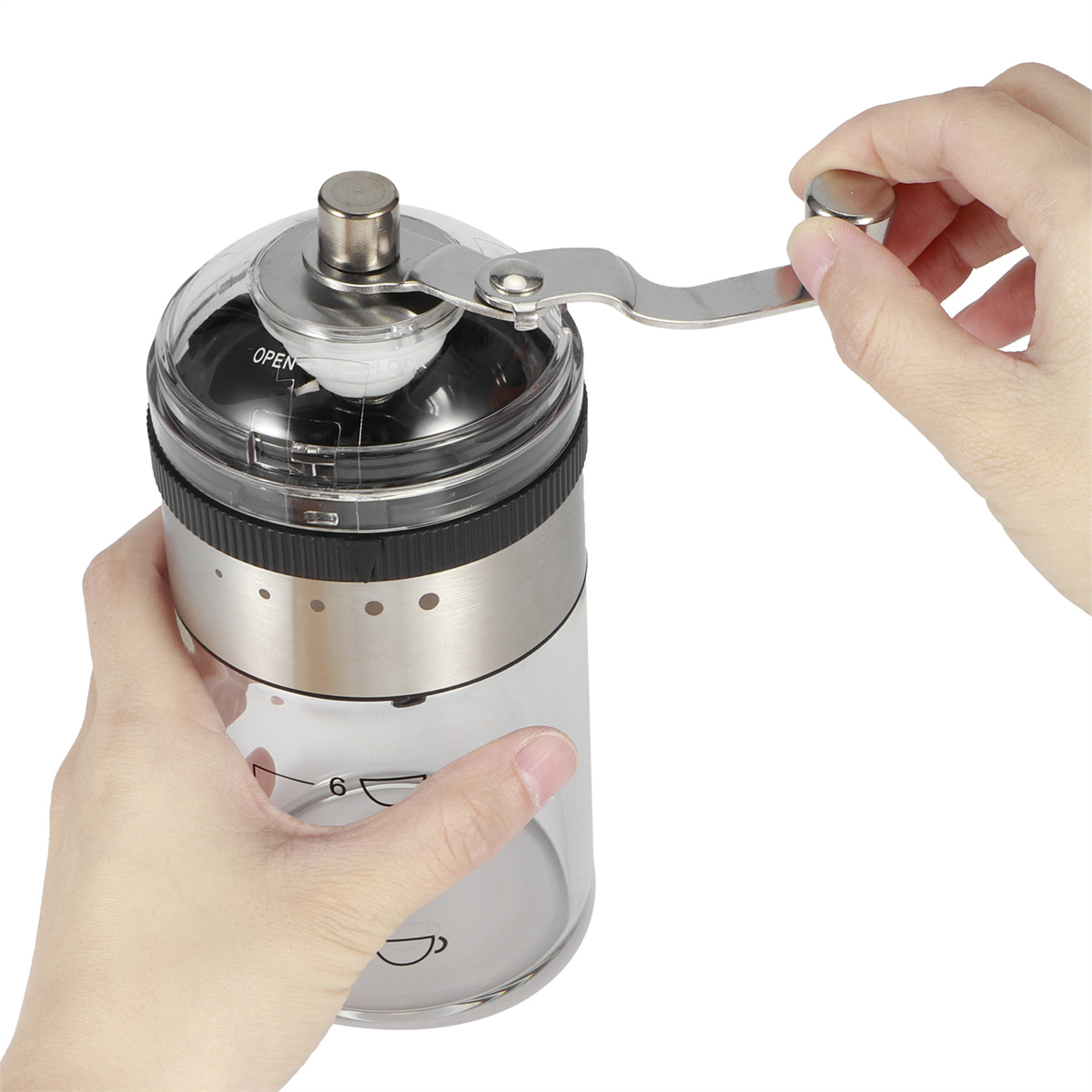 Hände benutzen manuelle Kaffeemühle. Klarer Behälter mit Kaffeebohnen und Mahlgradmarkierungen.