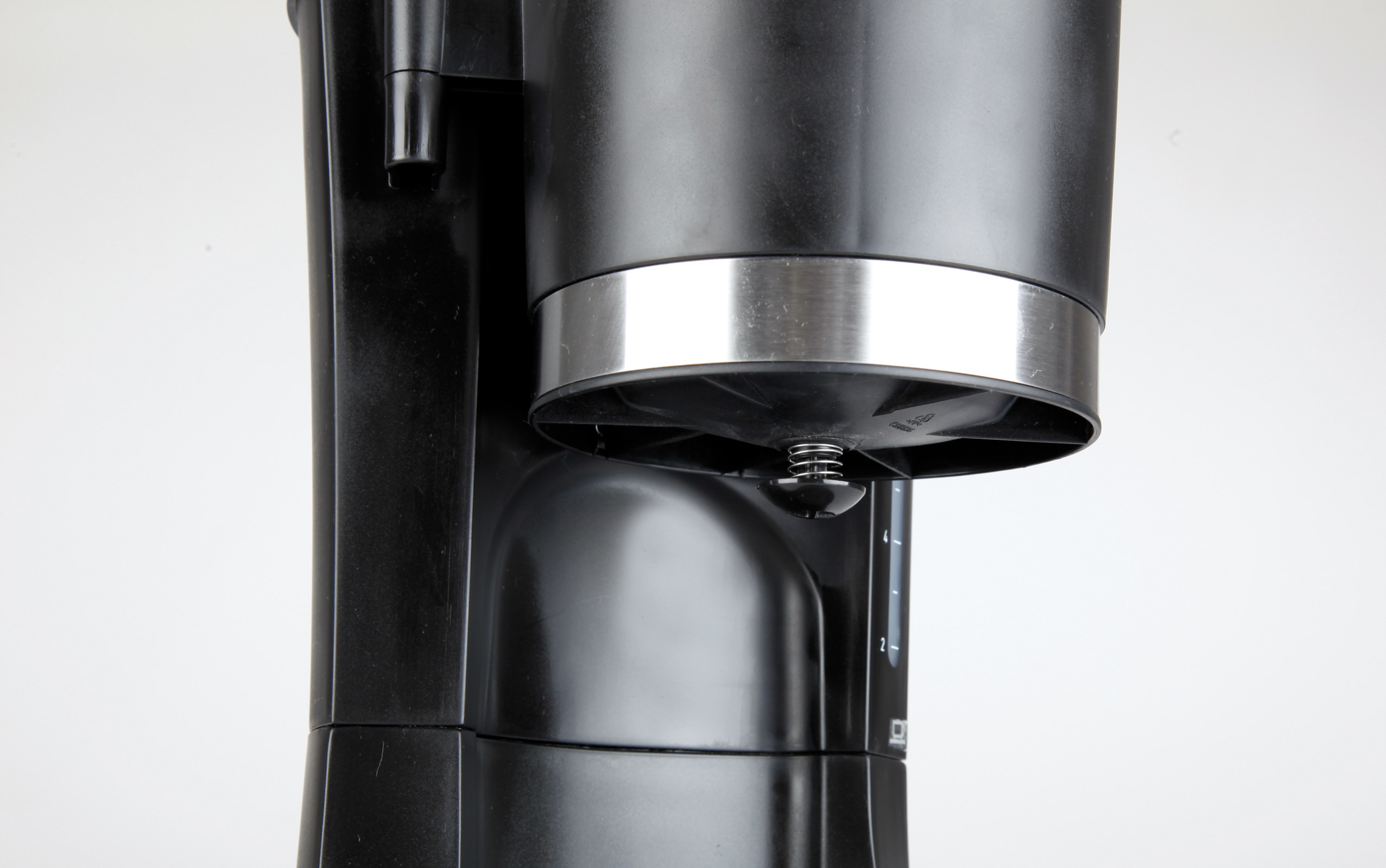 Zbliżenie czarnego ekspresu do kawy ze srebrnym pierścieniem i elementami wewnętrznymi.