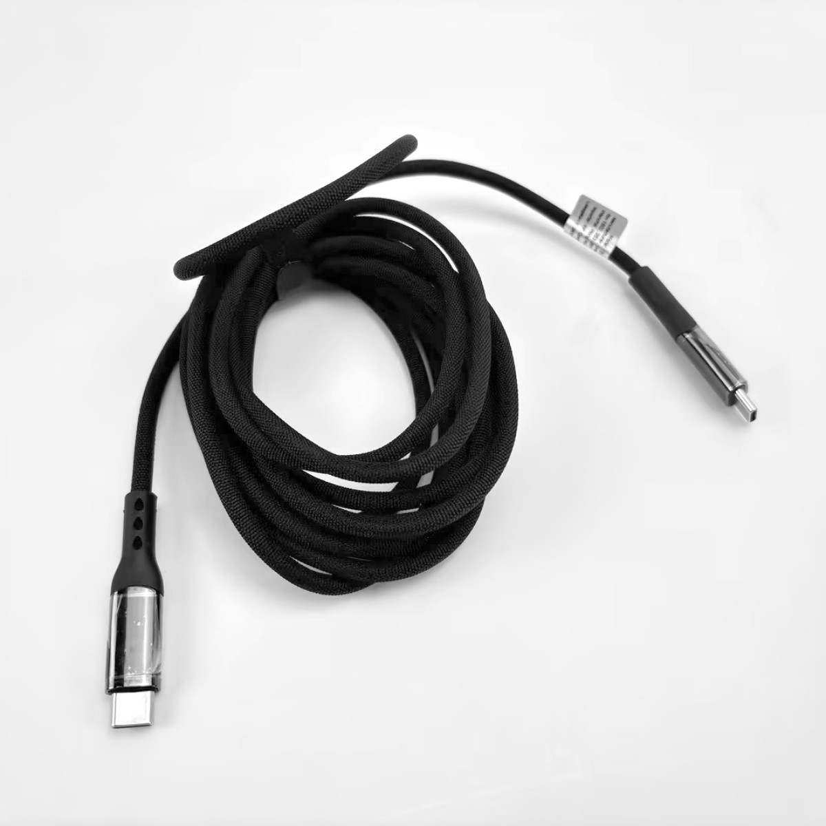 Ein schwarzes, aufgerolltes Ladekabel mit USB-C-Anschluss und Etikett.
