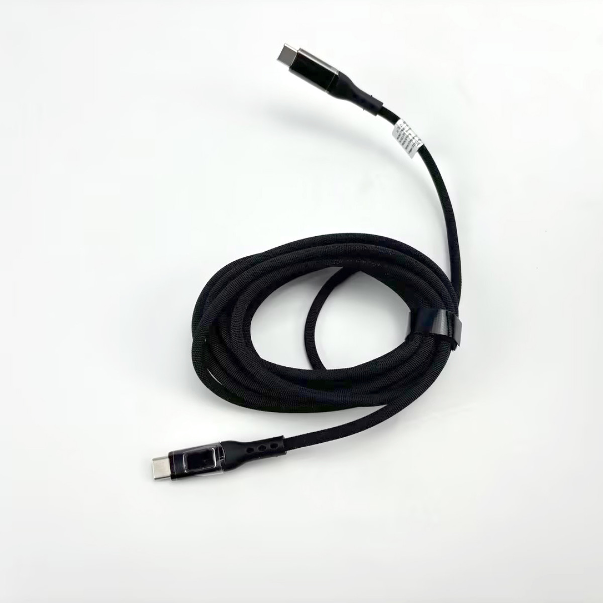 Schwarzes USB-C-Kabel, aufgerollt. Ein schwarzer Riemen ist um das Kabel gewickelt.