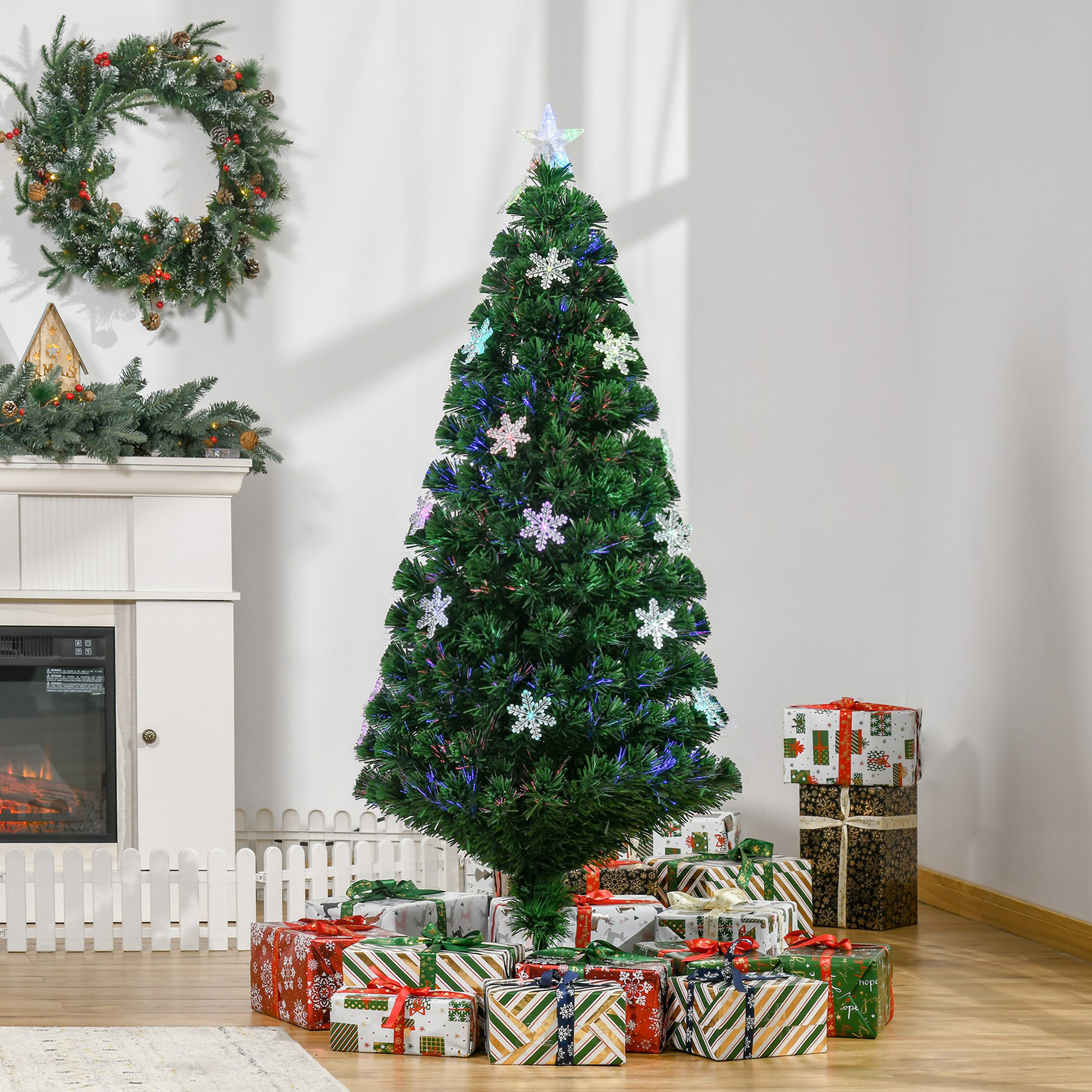 Un árbol de Navidad decorado con luces de copos de nieve, regalos alrededor de la base y una corona en el fondo.