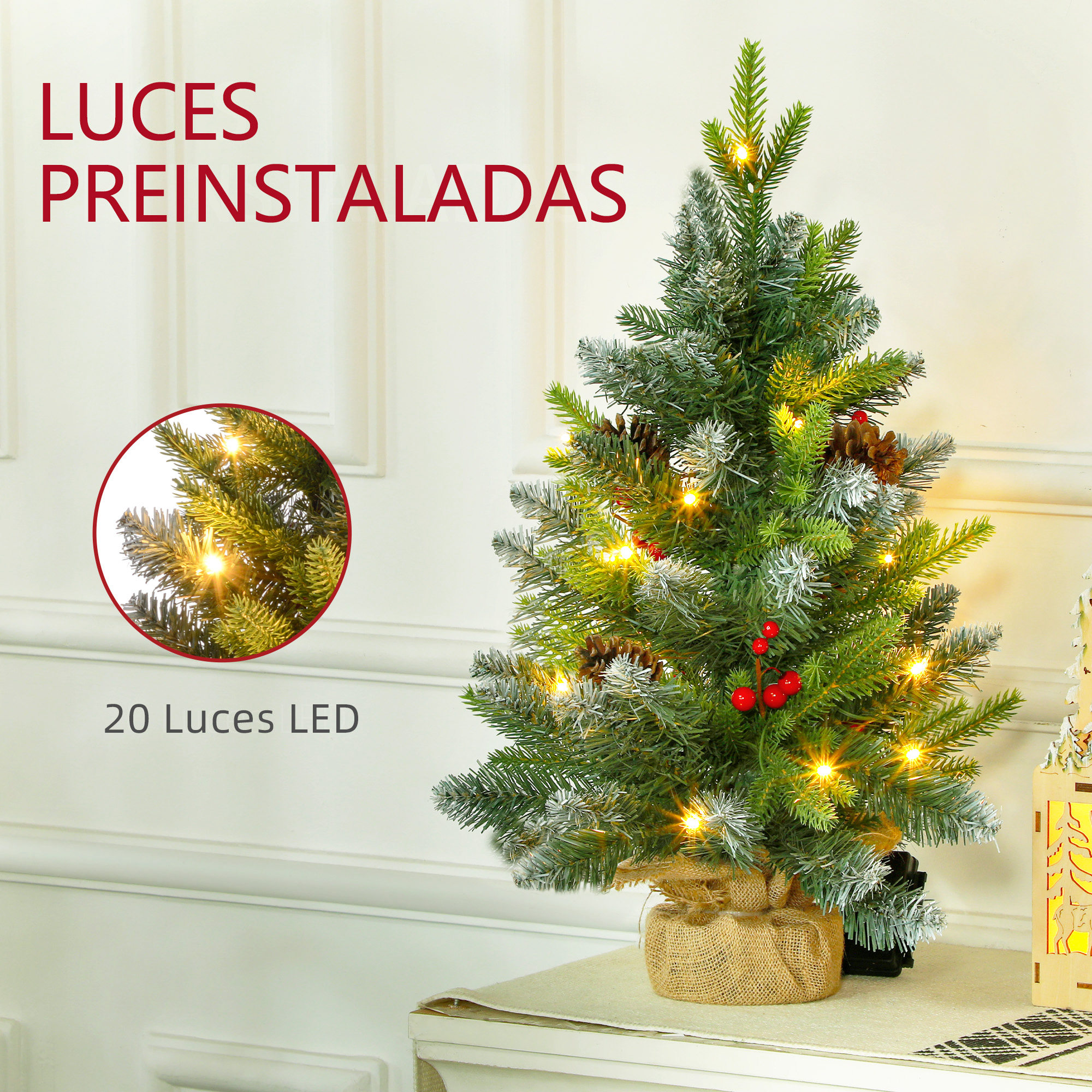 Pequeño árbol de navidad con luces y bayas rojas. El árbol está sobre una mesa. Pared blanca, texto rojo.