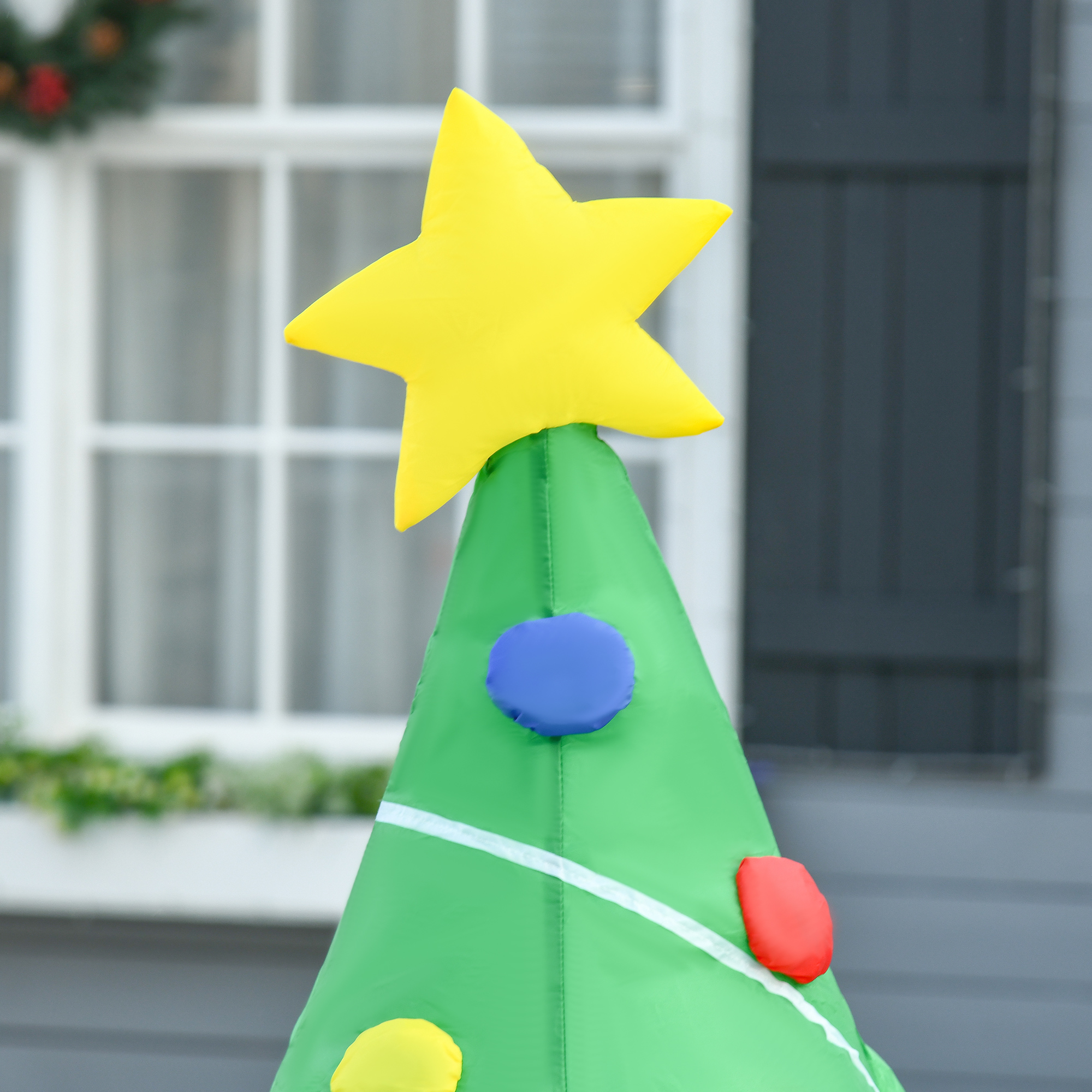 Árbol de Navidad inflable con estrella amarilla y círculos coloridos.