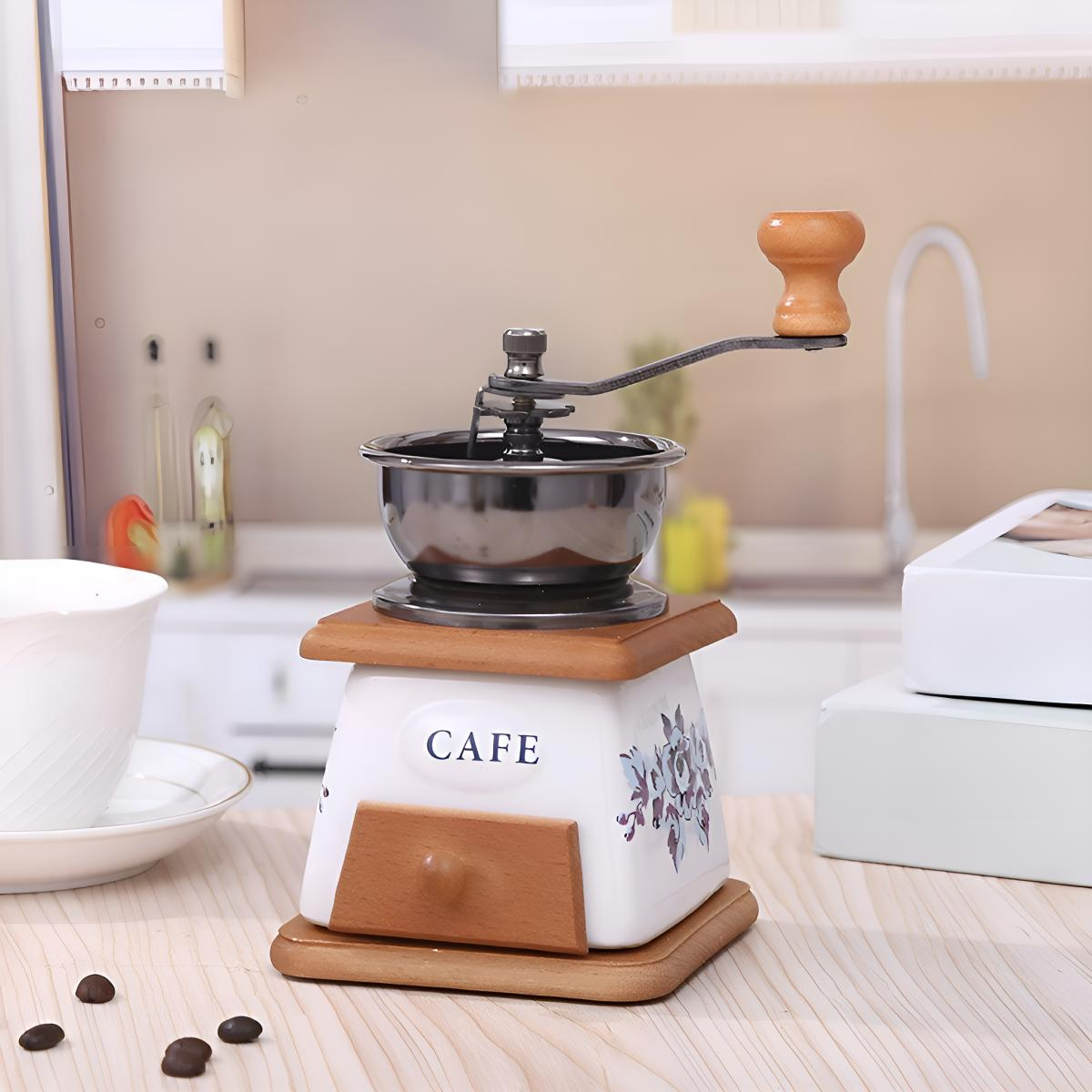 Manuelle Kaffeemühle auf Holzständer. Sie hat eine silberne Schüssel mit Griff. Auf der Basis steht 'CAFE'.