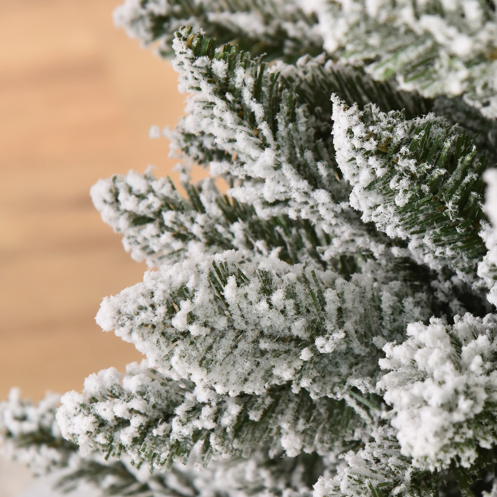 Primer plano de una rama de árbol de Navidad cubierta de nieve, con un fondo de madera.