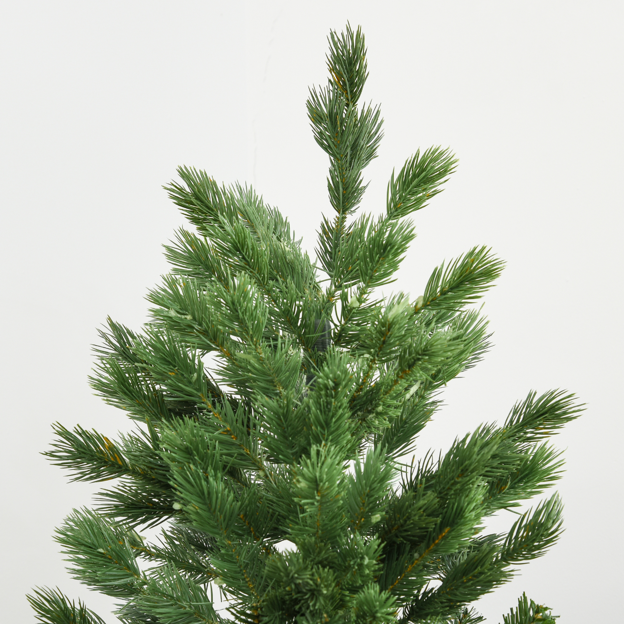Primer plano de la parte superior de un árbol de Navidad artificial verde, mostrando sus agujas.