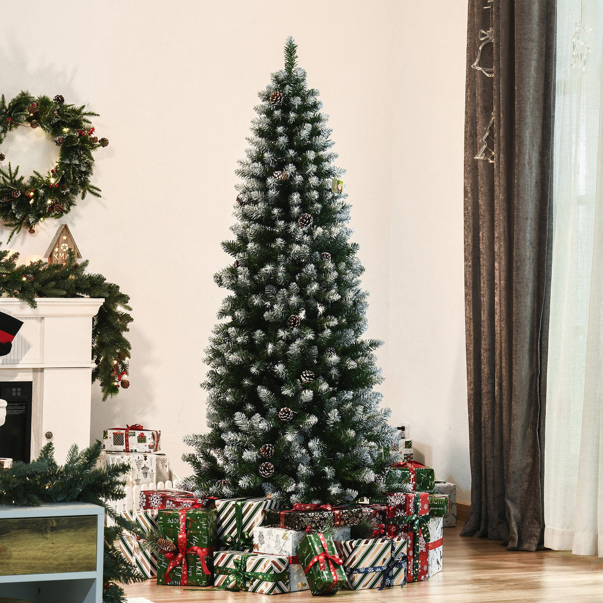 Árbol de Navidad decorado, regalos en la base. Habitación blanca, corona y otras decoraciones navideñas en el fondo.
