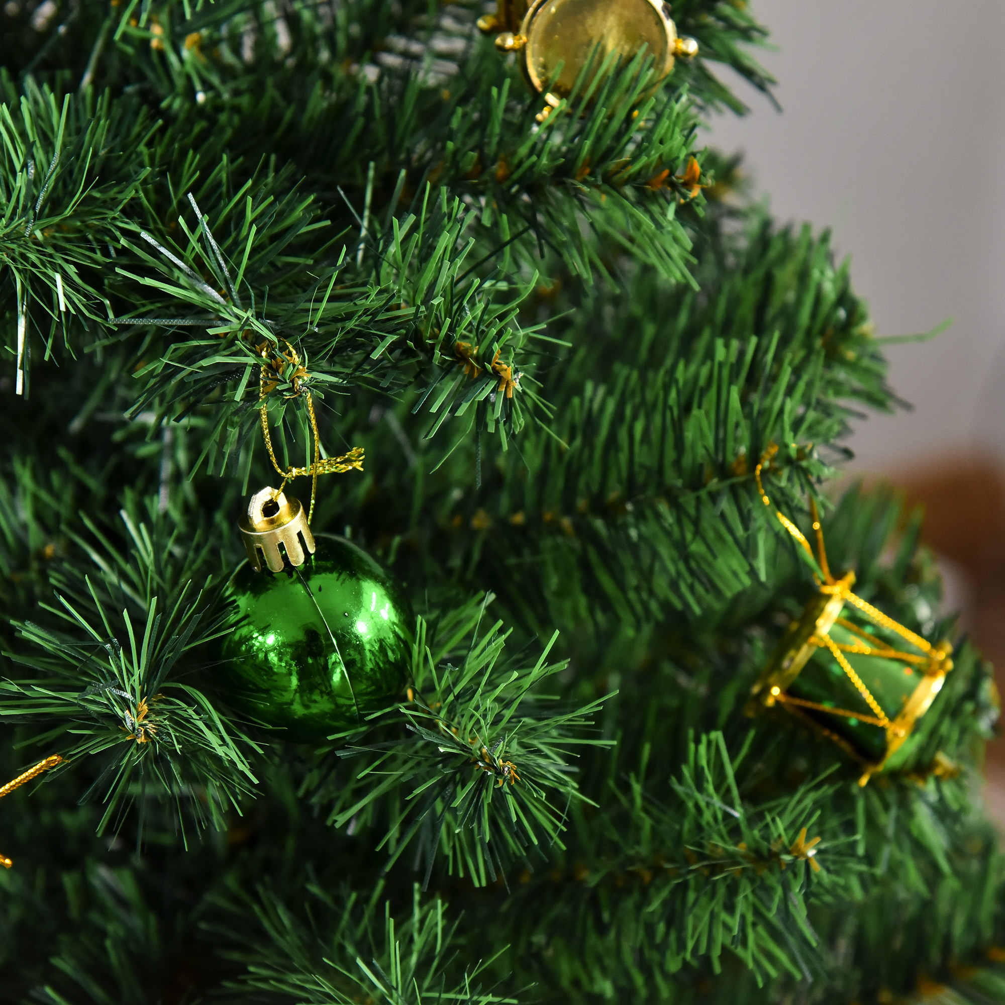 Primer plano de un árbol de Navidad decorado con adornos verdes y dorados.