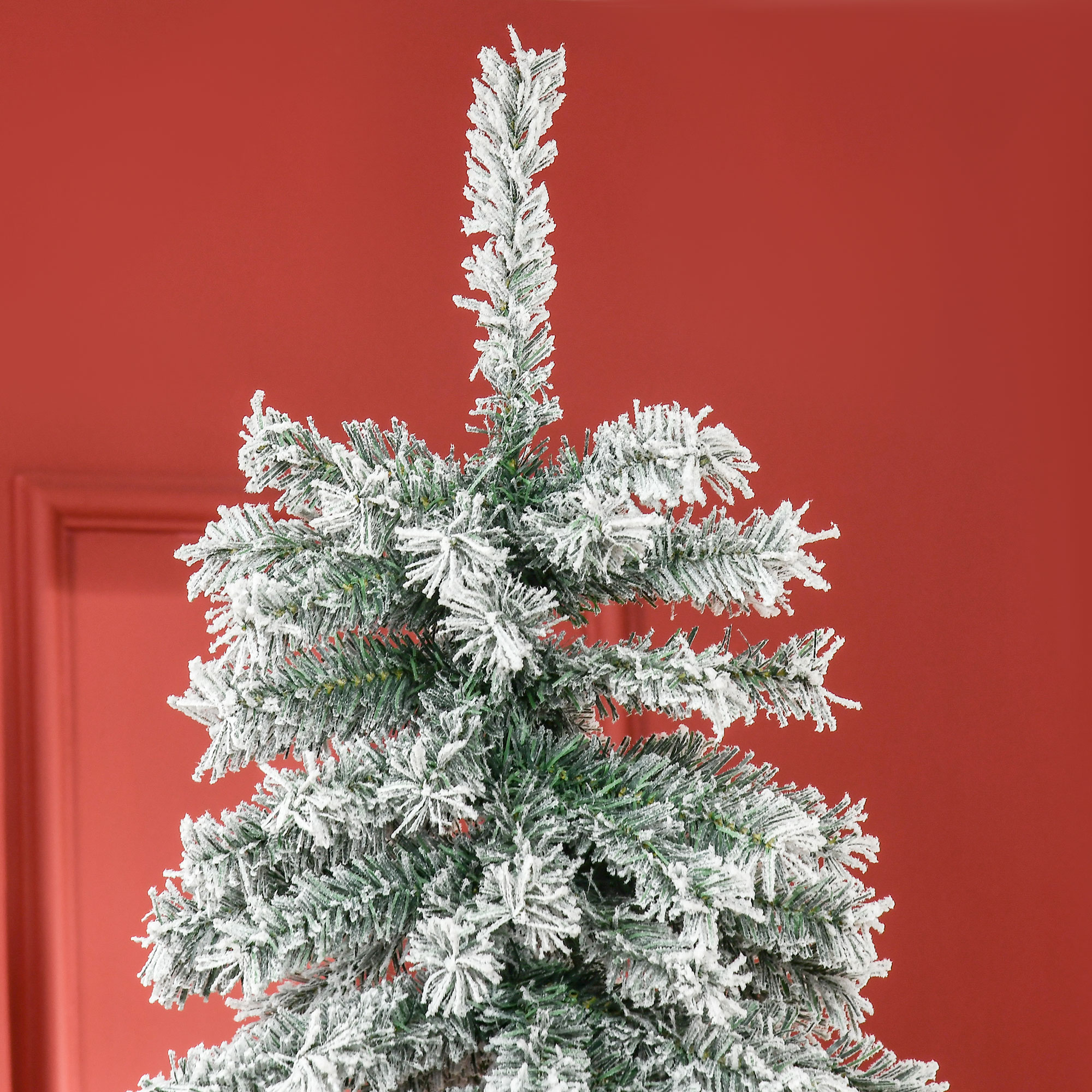 Primer plano de la cima de un árbol de Navidad nevado sobre fondo rojo.
