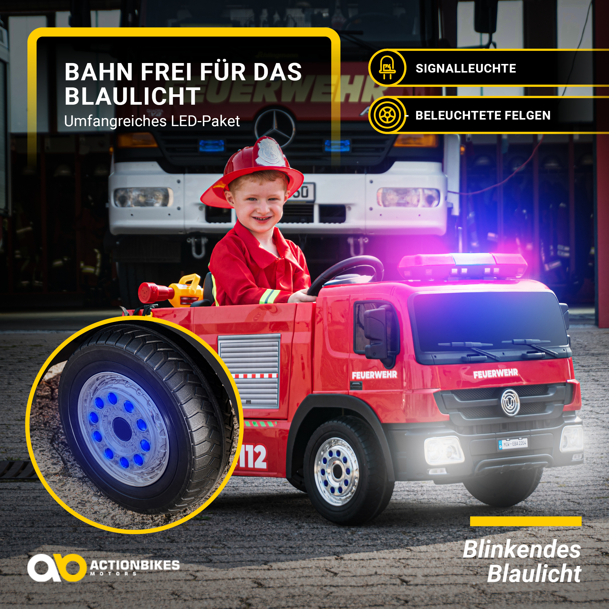 Ein Kind in einem Feuerwehrauto-Spielzeug, mit Lichtern und einem Feuerwehrauto im Hintergrund.
