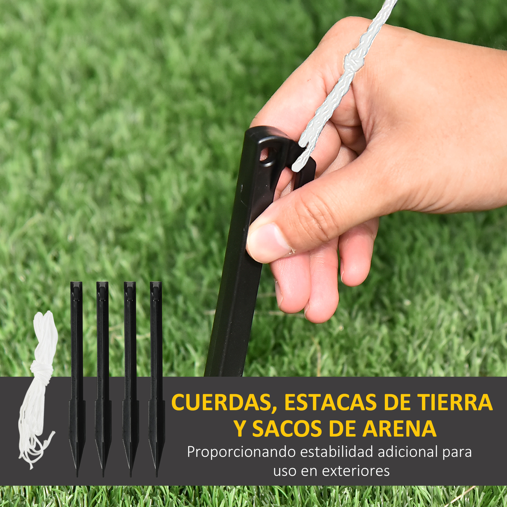 Mano sosteniendo una estaca negra cerca de otras estacas y cuerda sobre hierba.