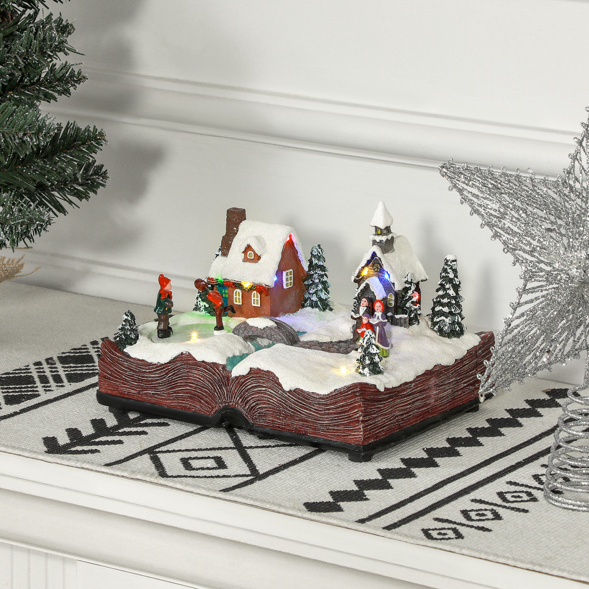 Exhibición de un pueblo navideño en un libro abierto. Casas, figuras y paisaje nevado con luces.