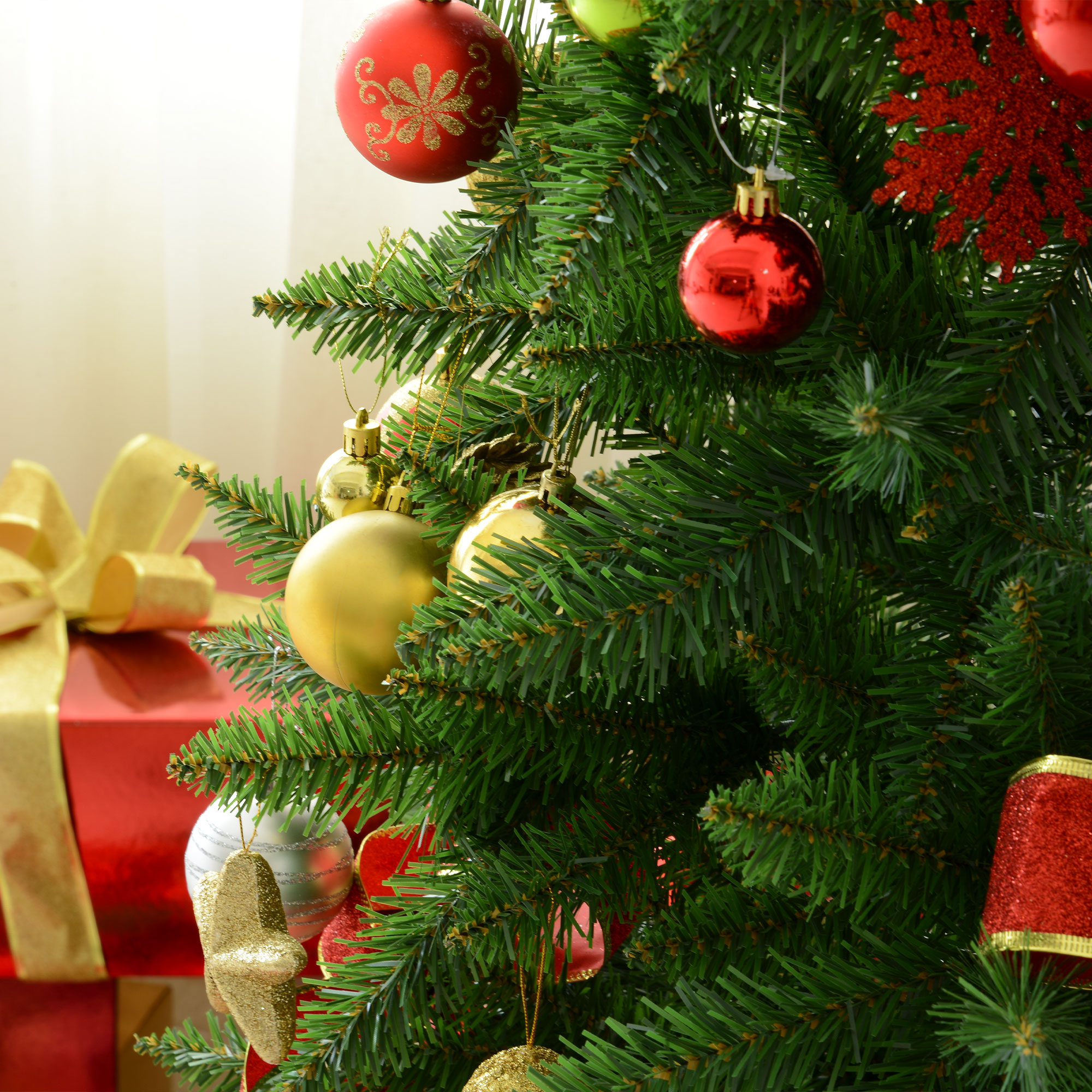 Árbol de Navidad con adornos, bolas y cintas rojas y doradas, primer plano.