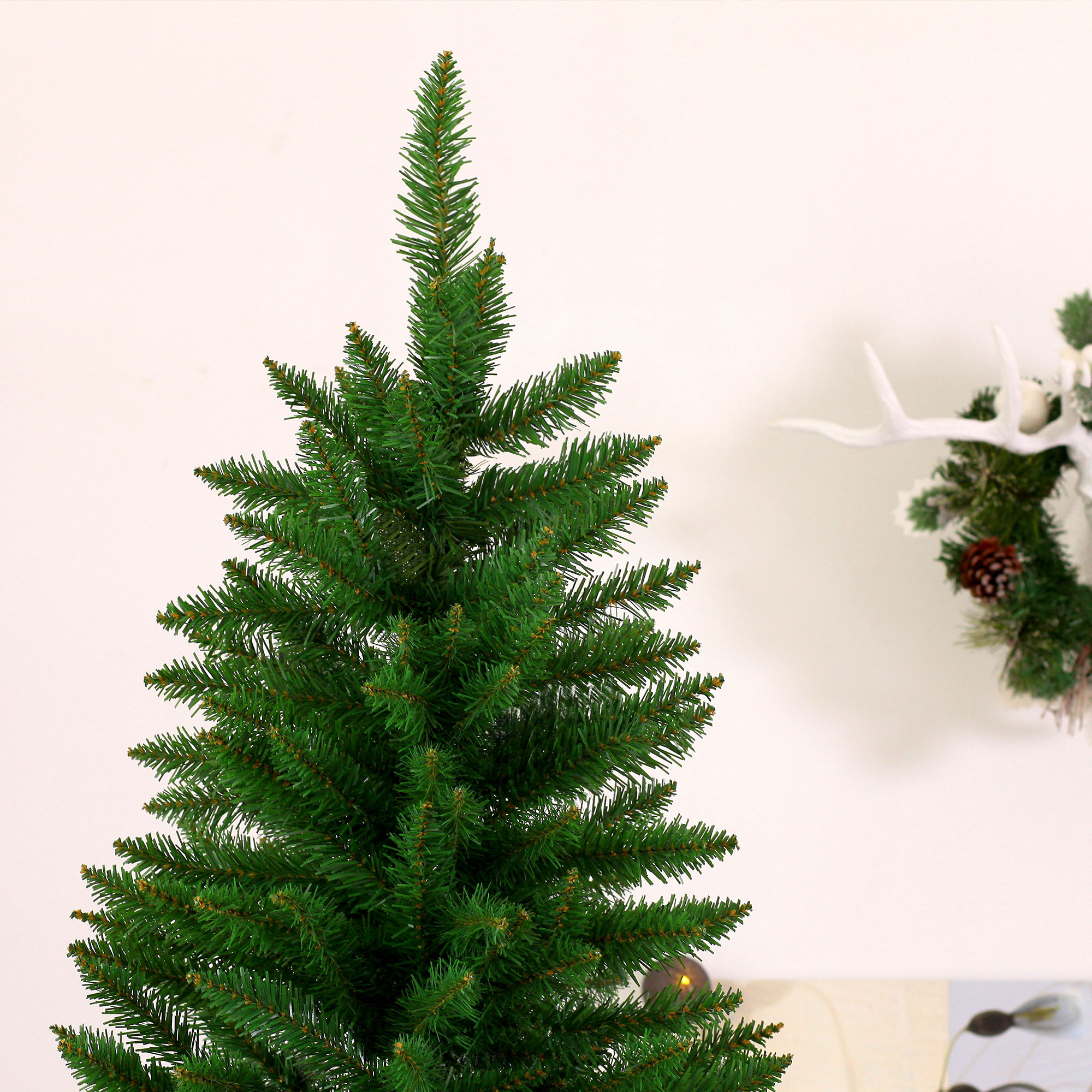 Primer plano de un árbol de Navidad verde. El árbol tiene agujas verdes y está sobre un fondo blanco.
