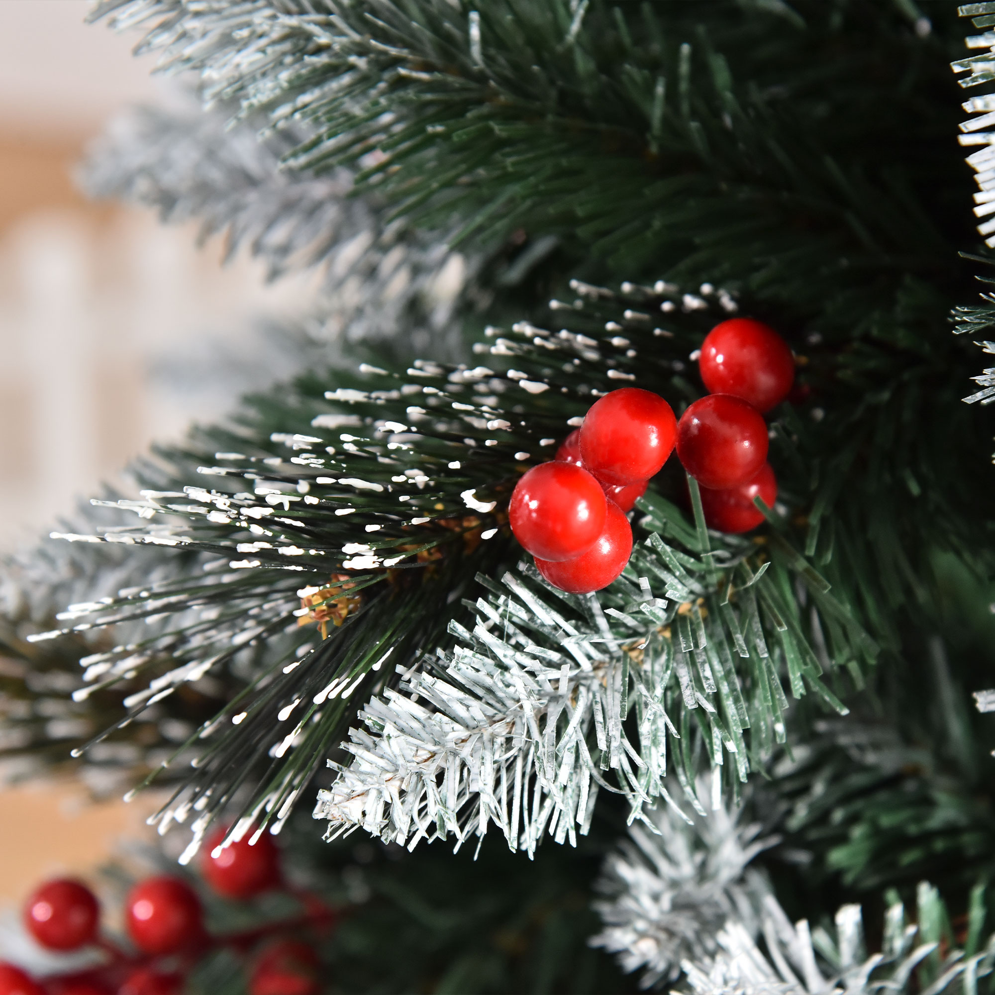 Primer plano de una rama de árbol de Navidad con bayas rojas, espolvoreada con nieve artificial blanca.
