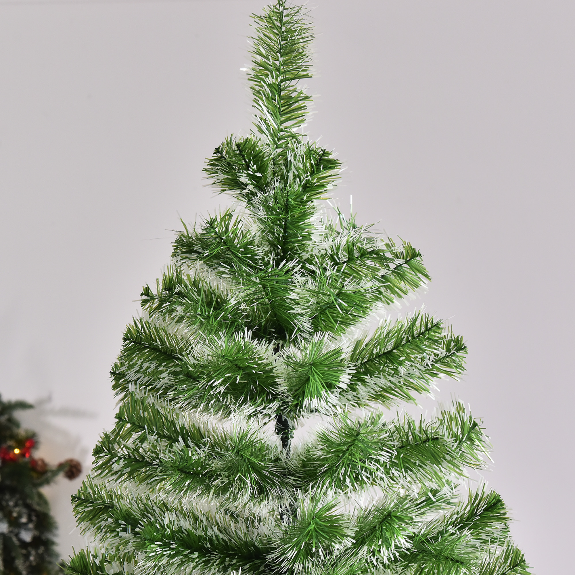 Primer plano de un árbol de Navidad verde con decoraciones blancas y esponjosas en las ramas sobre fondo blanco.