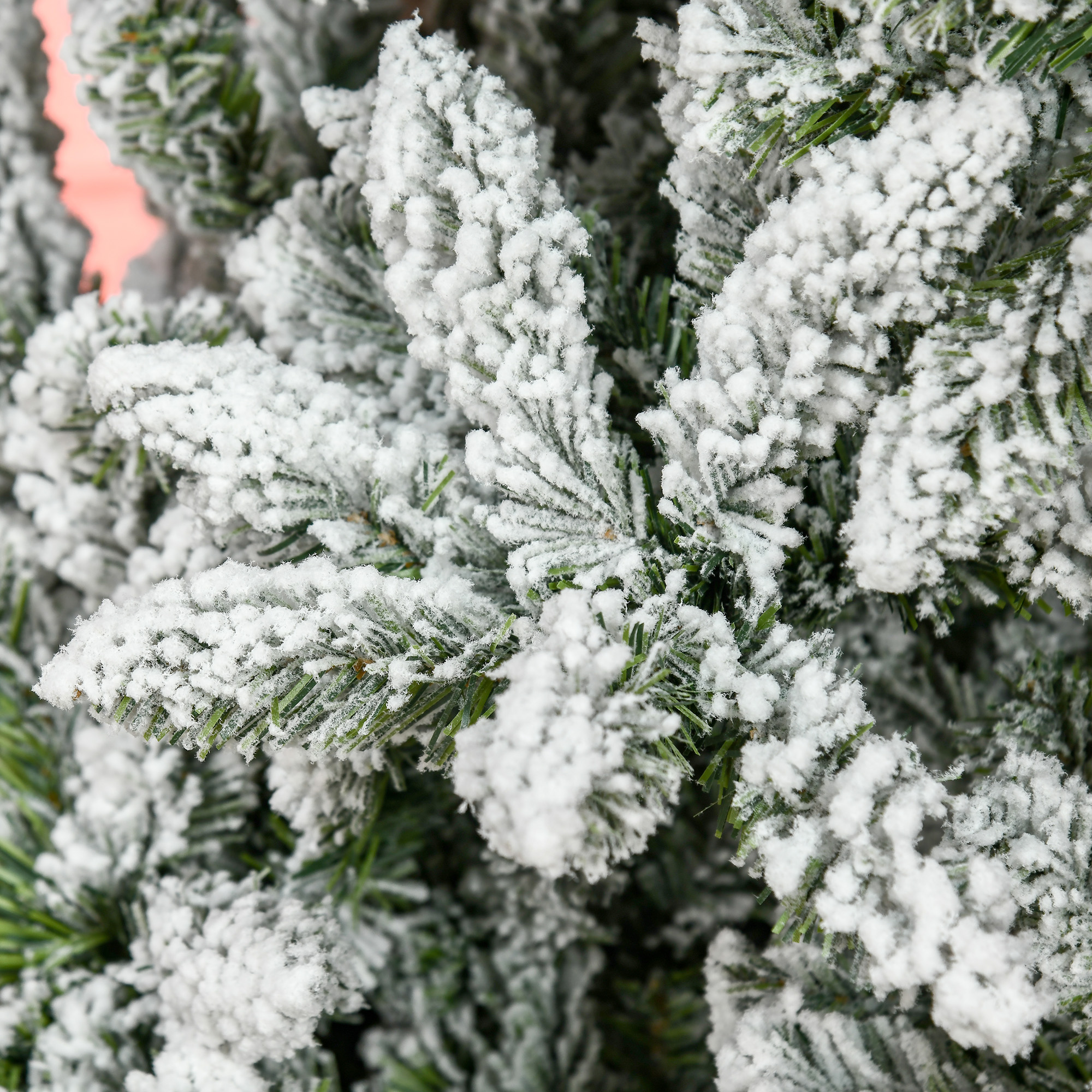 Primer plano de una rama de árbol de Navidad cubierta con material blanco, similar a la nieve.