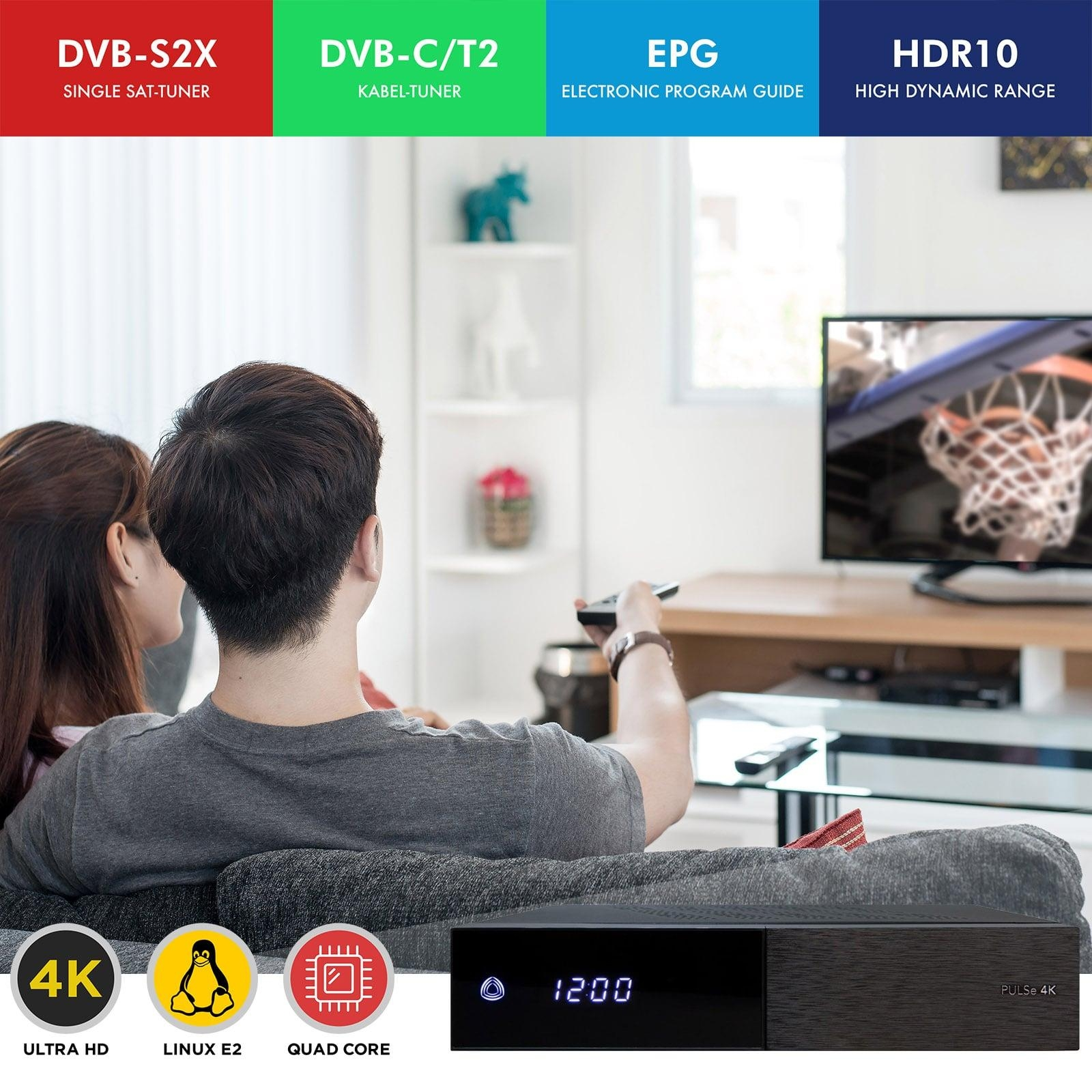 Ein Paar schaut fern. Eine schwarze Set-Top-Box und Programminfo darunter.