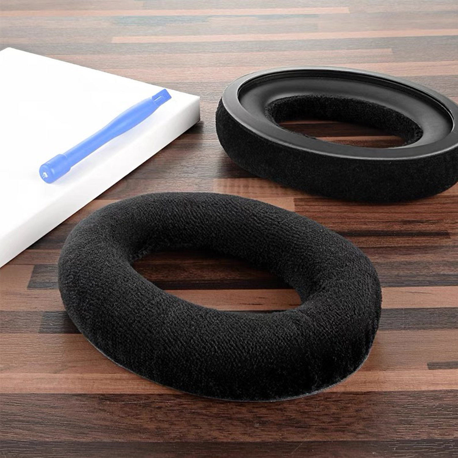 Czarne nauszniki, niebieskie narzędzie i biała pianka na drewnianej powierzchni.