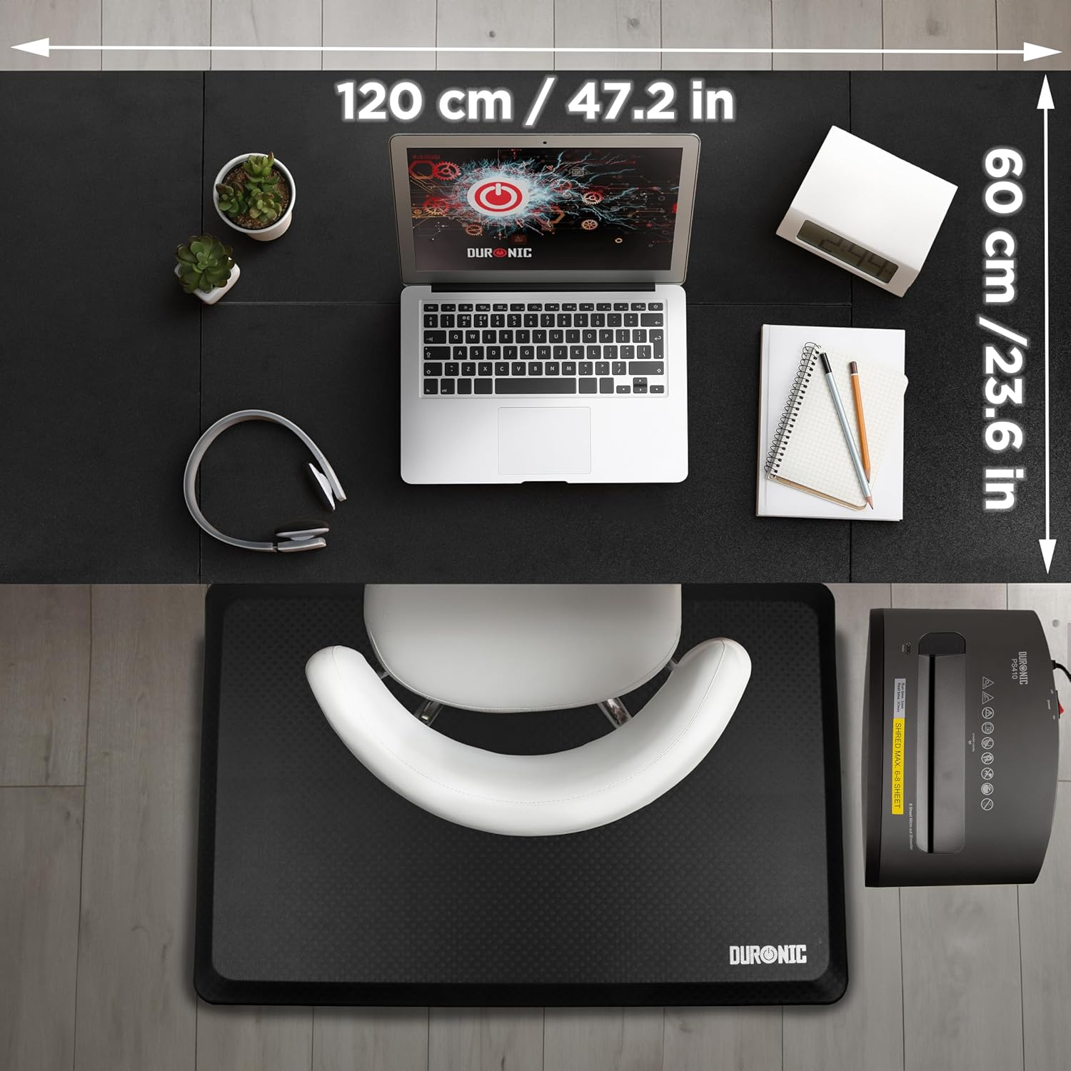 Ein Büroaufbau auf einer schwarzen Matte mit Laptop, Kopfhörern und Aktenvernichter, Maße angegeben.