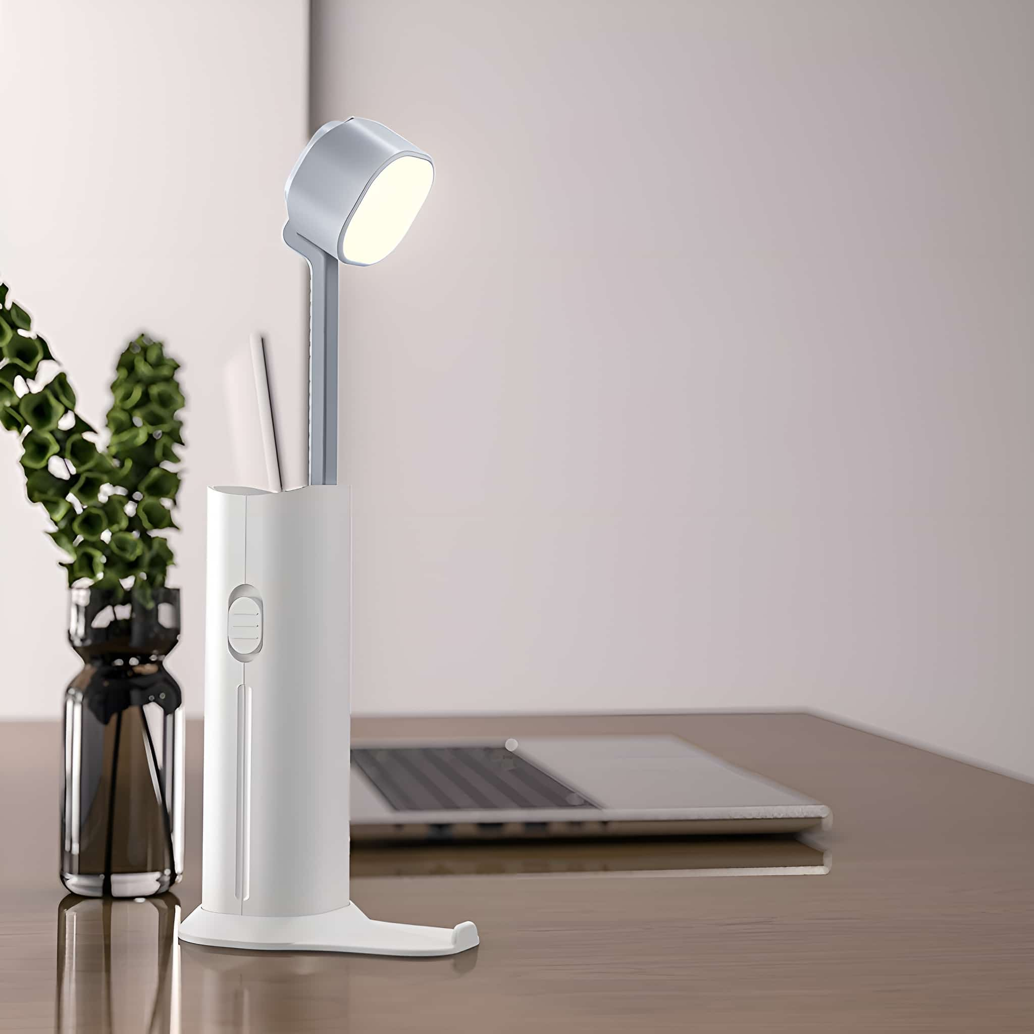 Schreibtischlampe mit Stifthalter und Laptop.