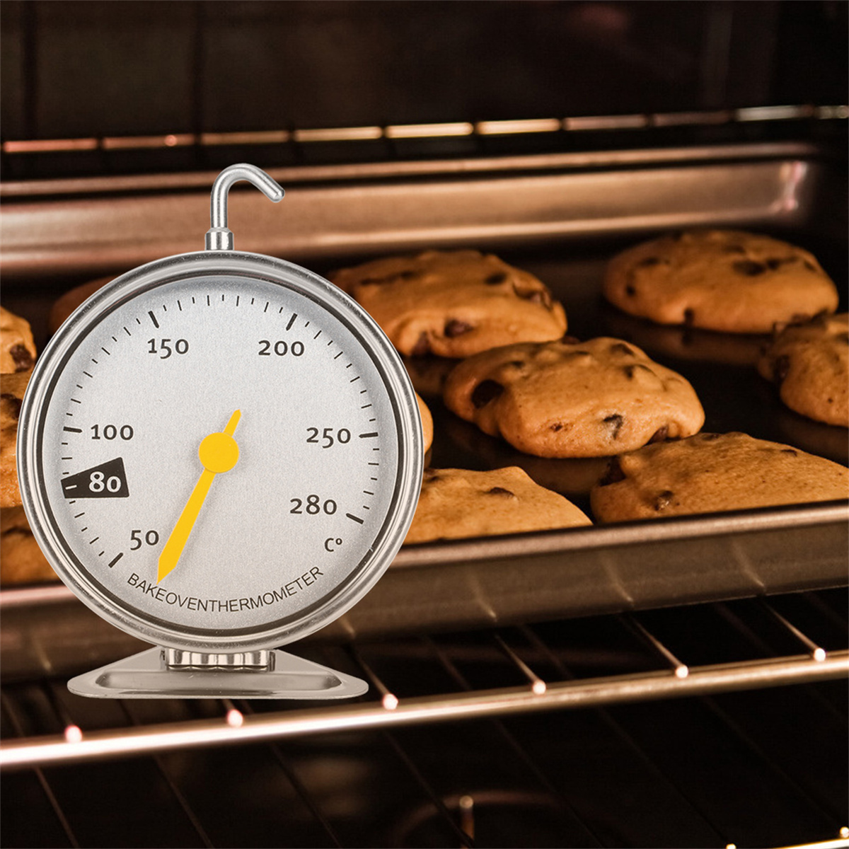Ofen mit Thermometer, das hohe Temperatur anzeigt, und Blech mit Keksen.