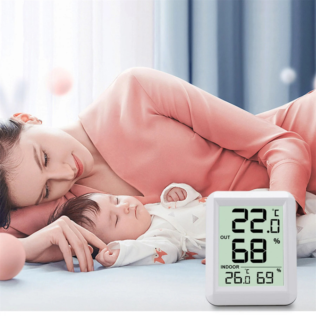 Frau und Baby schlafen mit einem digitalen Thermometer, das Temperatur und Luftfeuchtigkeit anzeigt.