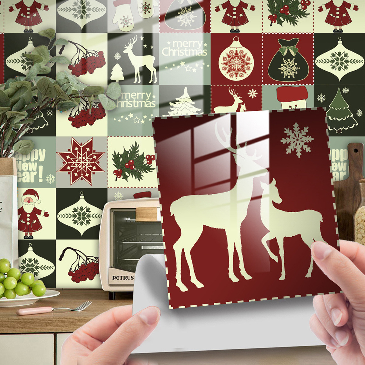 Hände halten eine Weihnachtsdekoration mit Hirschen. Hintergrund zeigt Weihnachtskacheln.