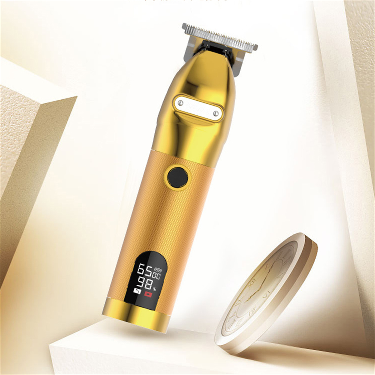 Ein goldener Haarschneider. Er hat eine Digitalanzeige und ist auf einer weißen Oberfläche mit einer Goldmünze daneben platziert.