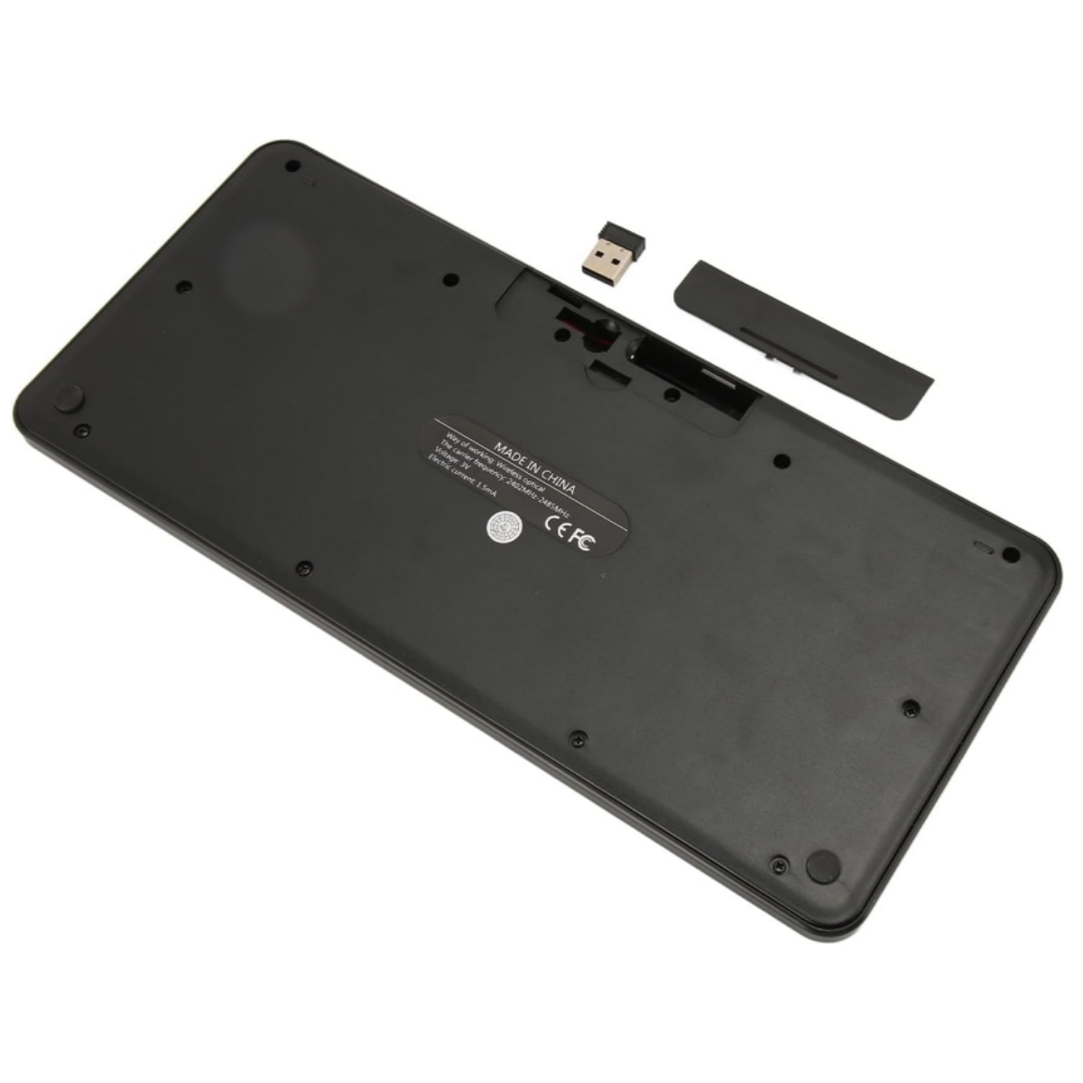 Die Unterseite einer schwarzen Tastatur mit einem drahtlosen USB-Empfänger und einer Batteriefachabdeckung. Made in China-Etikett.