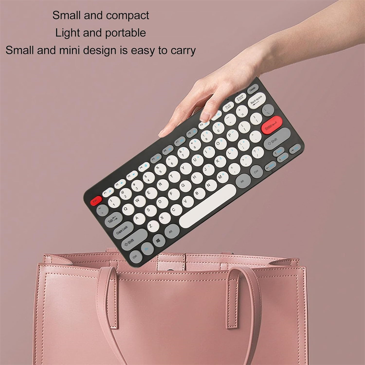 Eine Hand, die eine kleine Tastatur über einer rosa Tasche hält. Die Tastatur ist schwarz mit weißen Tasten.