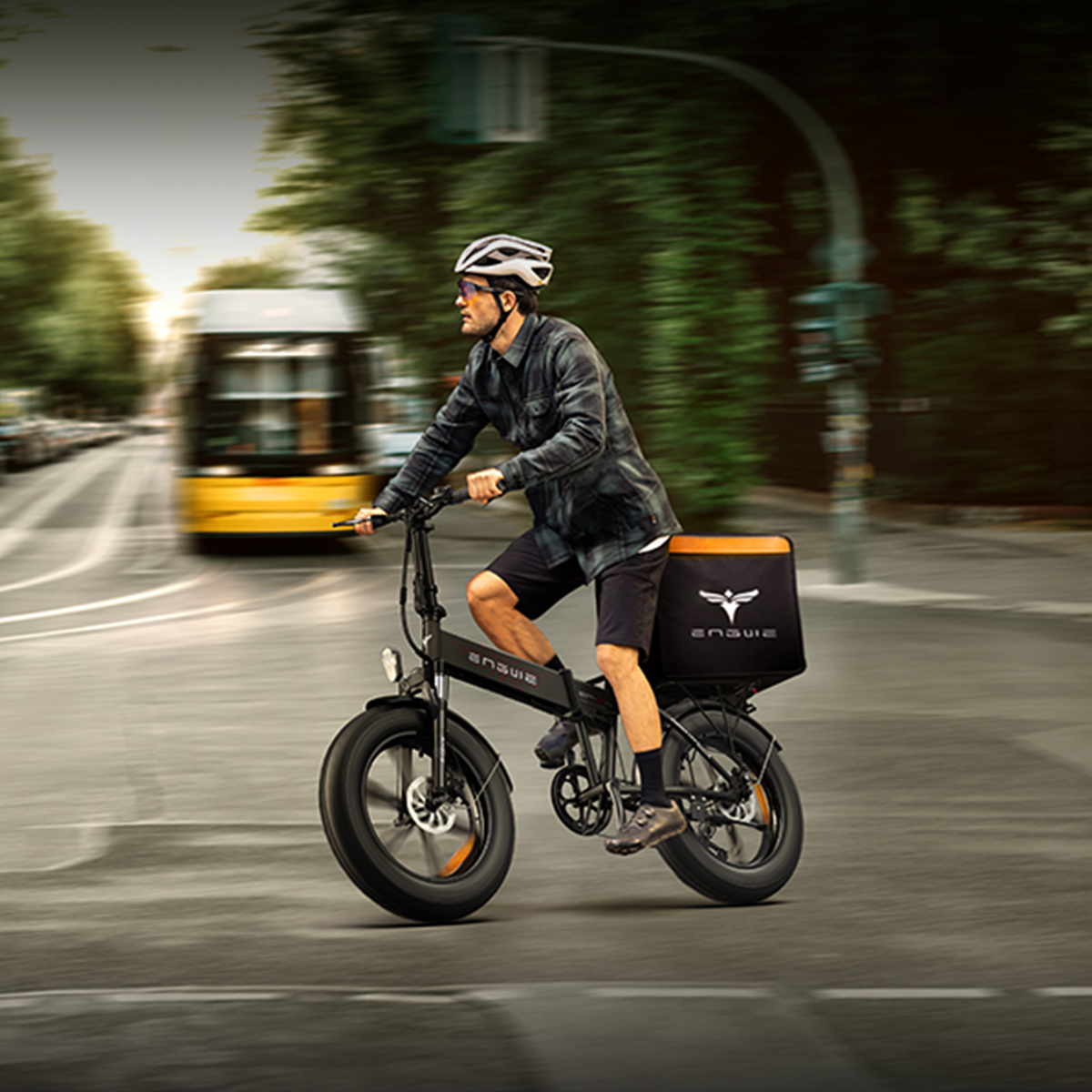 Una persona su una e-bike nera con un vano portaoggetti che percorre una strada.
