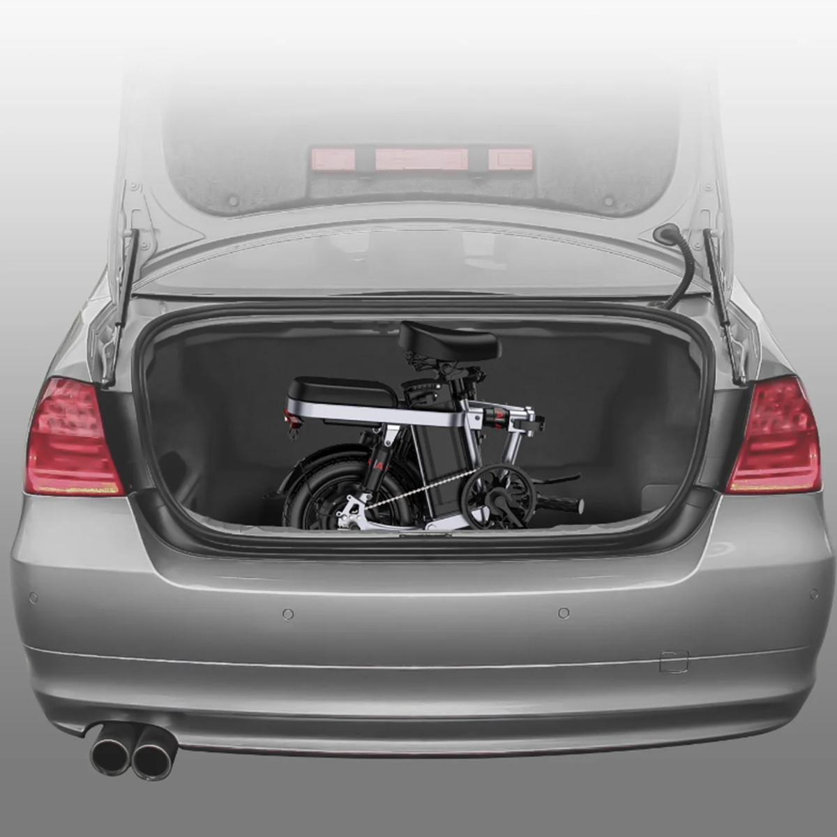 Otwarty srebrny bagażnik samochodu z czarnym, złożonym rowerem w środku.