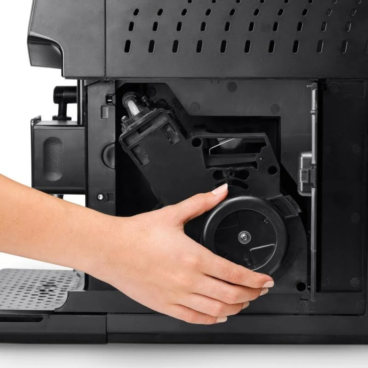 Dłoń osoby wyjmująca część z wnętrza czarnego ekspresu do kawy.