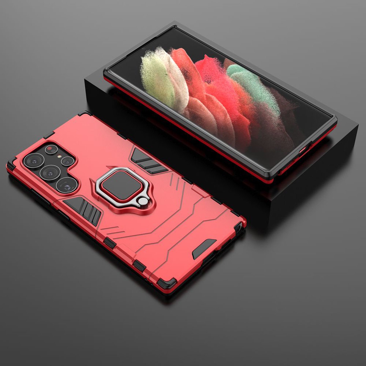 Twee telefoonhoesjes, een rode met ring en een zwarte, op een zwart oppervlak.