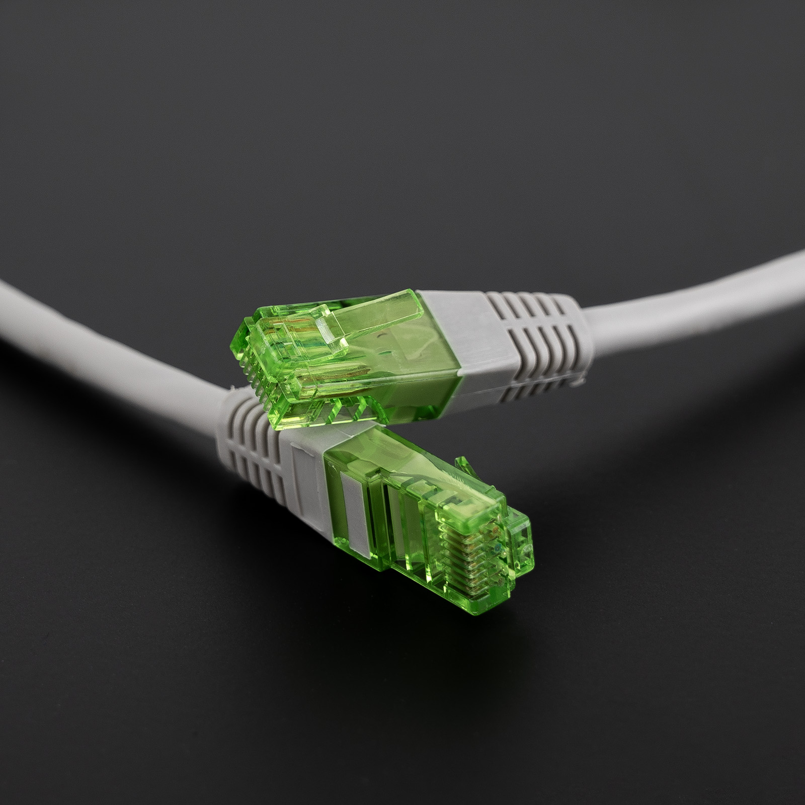 Twee grijze Ethernet-kabels met groene connectoren, tegen donkergrijze achtergrond.