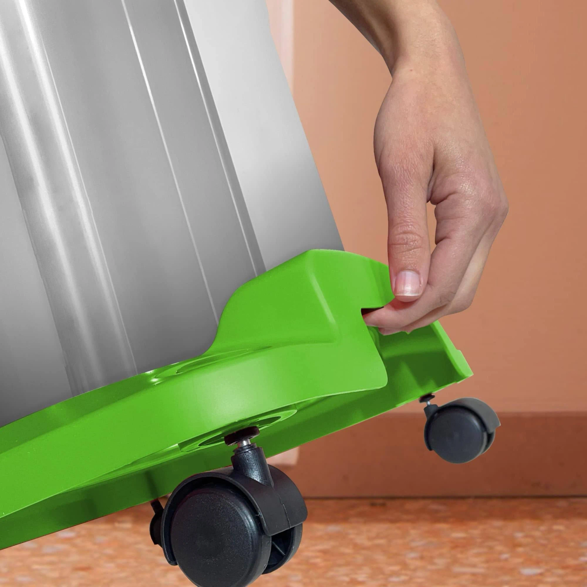 Una mano che attacca una ruota a una base verde, con altre ruote visibili.