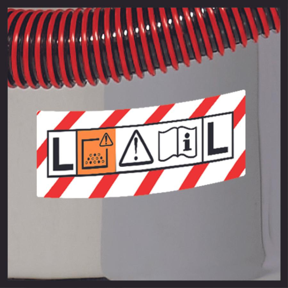 Naklejka z czerwono-białymi paskami oraz tekstem i symbolami ostrzegawczymi na maszynie.