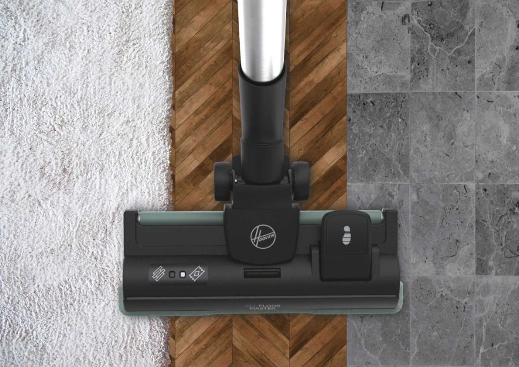 Vacuum cleaner head cleaning a carpet, wood, and tiled floor. The vacuum head is black and gray.