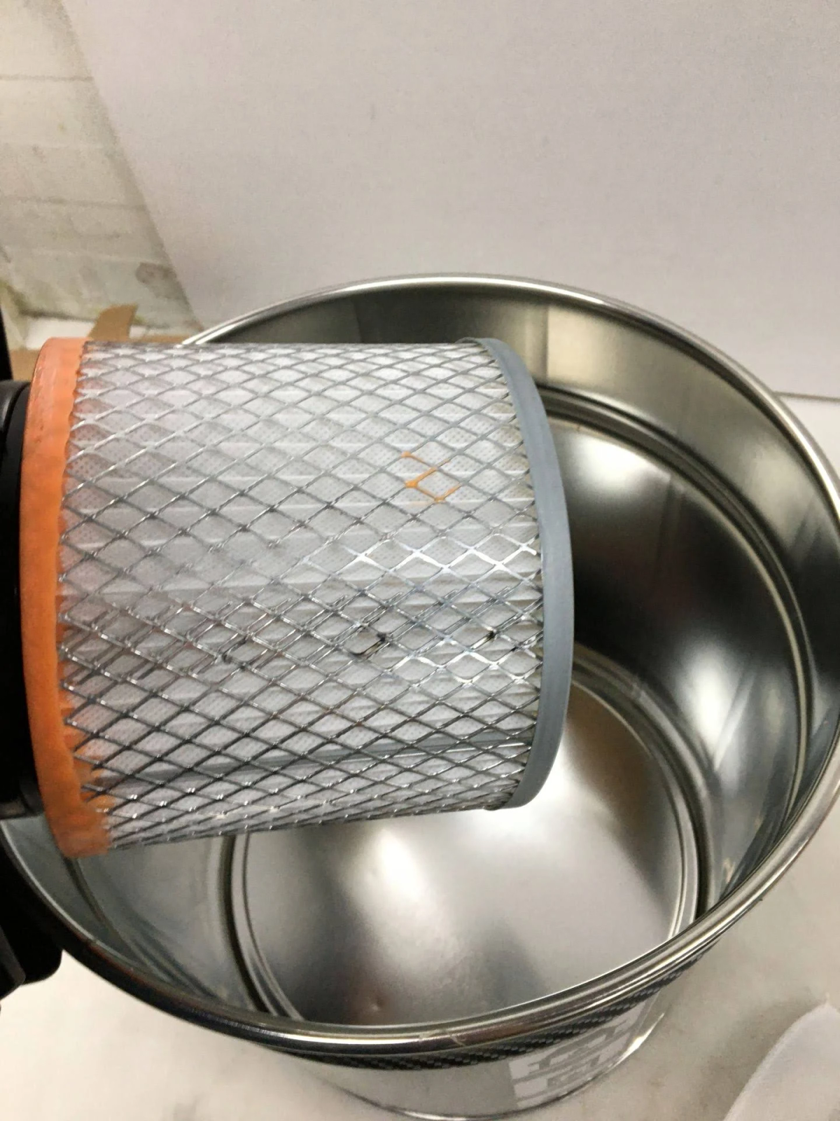 Filtro per aspirapolvere, che mostra la rete filtrante, all'interno di un contenitore metallico.