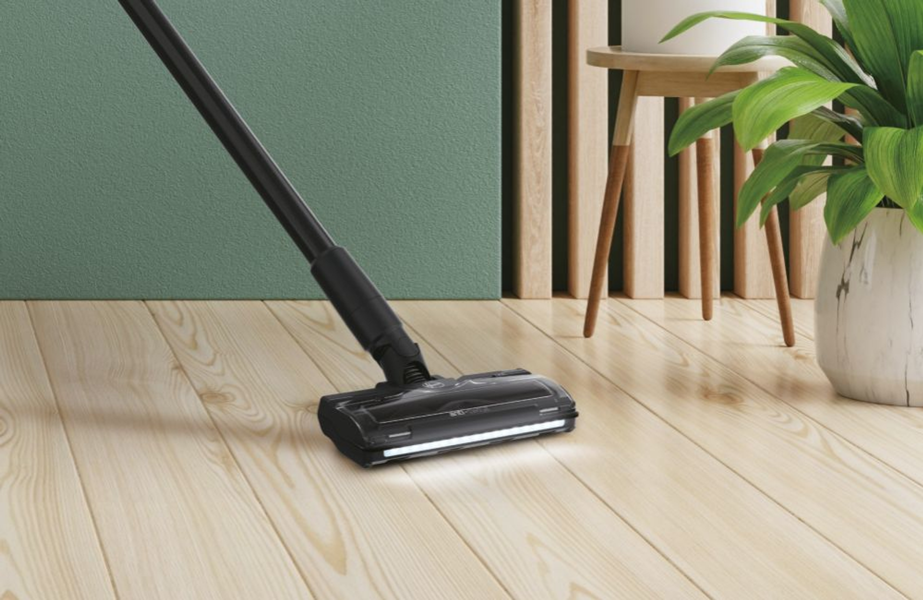 Zbliżenie głowicy odkurzacza z długim uchwytem na drewnianej podłodze.