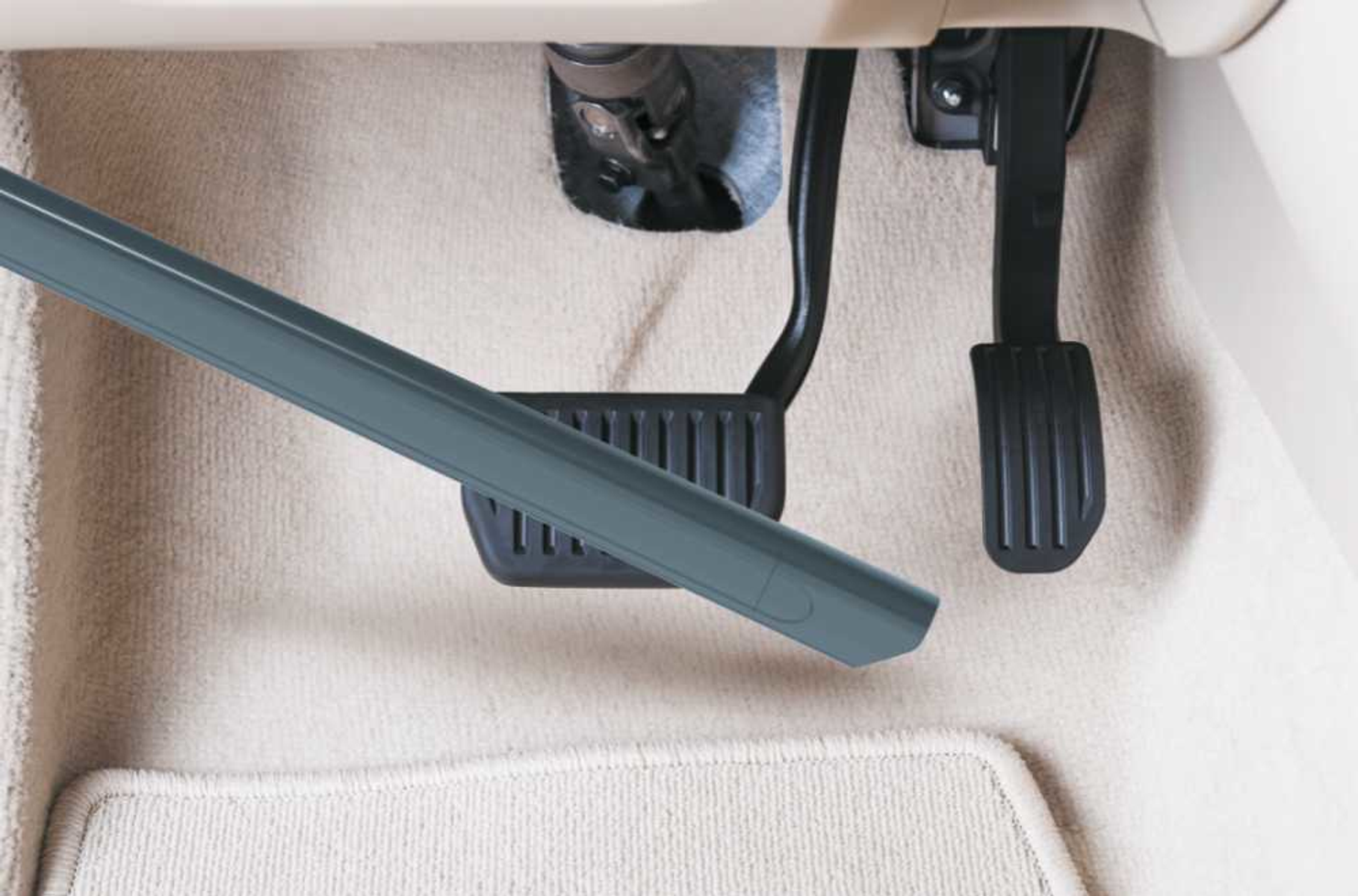 Końcówka odkurzacza czyszcząca wnętrze samochodu, w pobliżu pedałów.