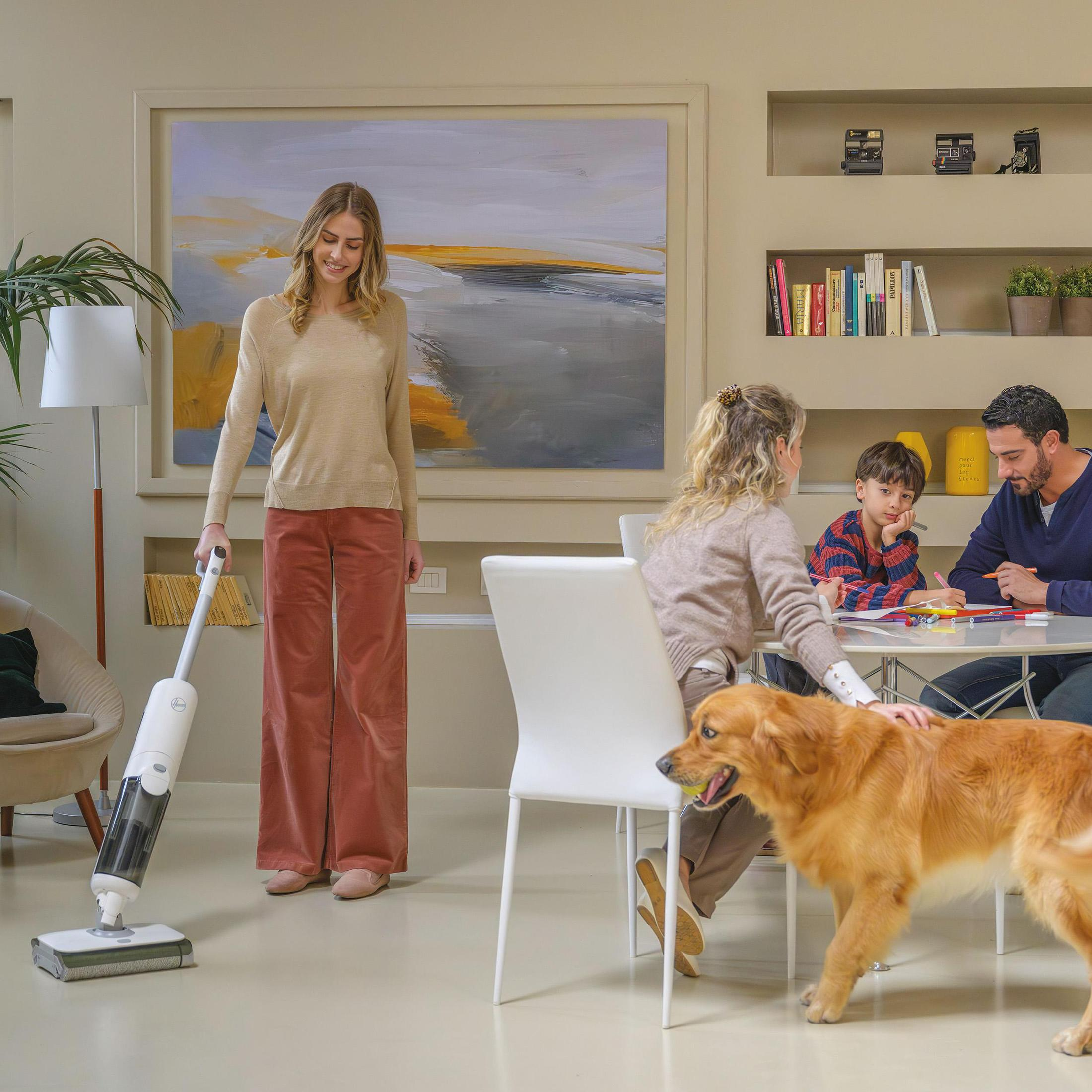 Femme avec un aspirateur-serpillère, famille à table, chien avec une balle, cadre salon.
