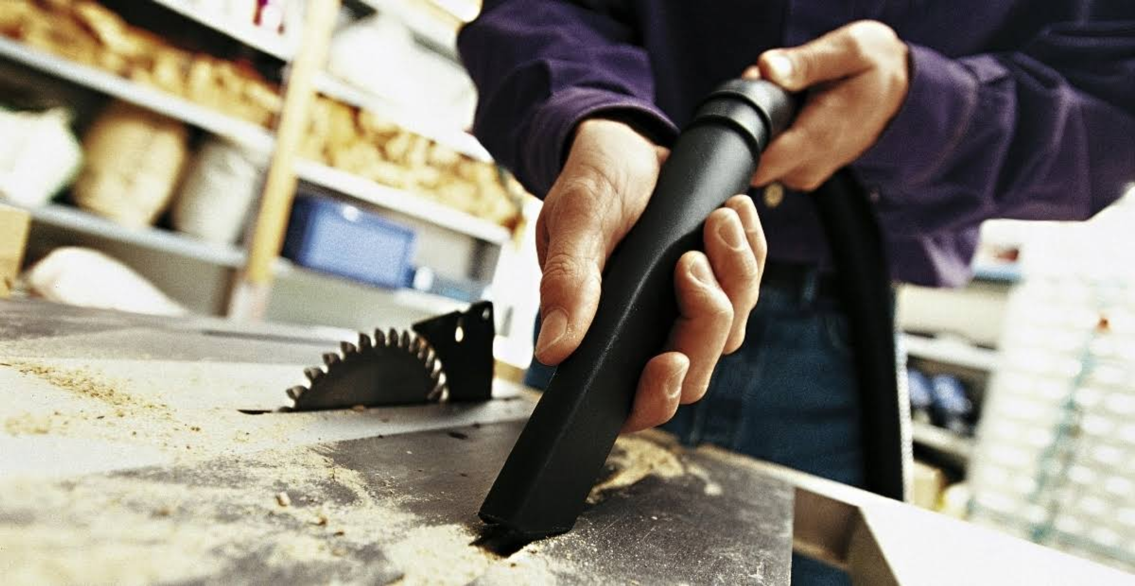 Una persona usa un accessorio nero per aspirapolvere per pulire il legno.