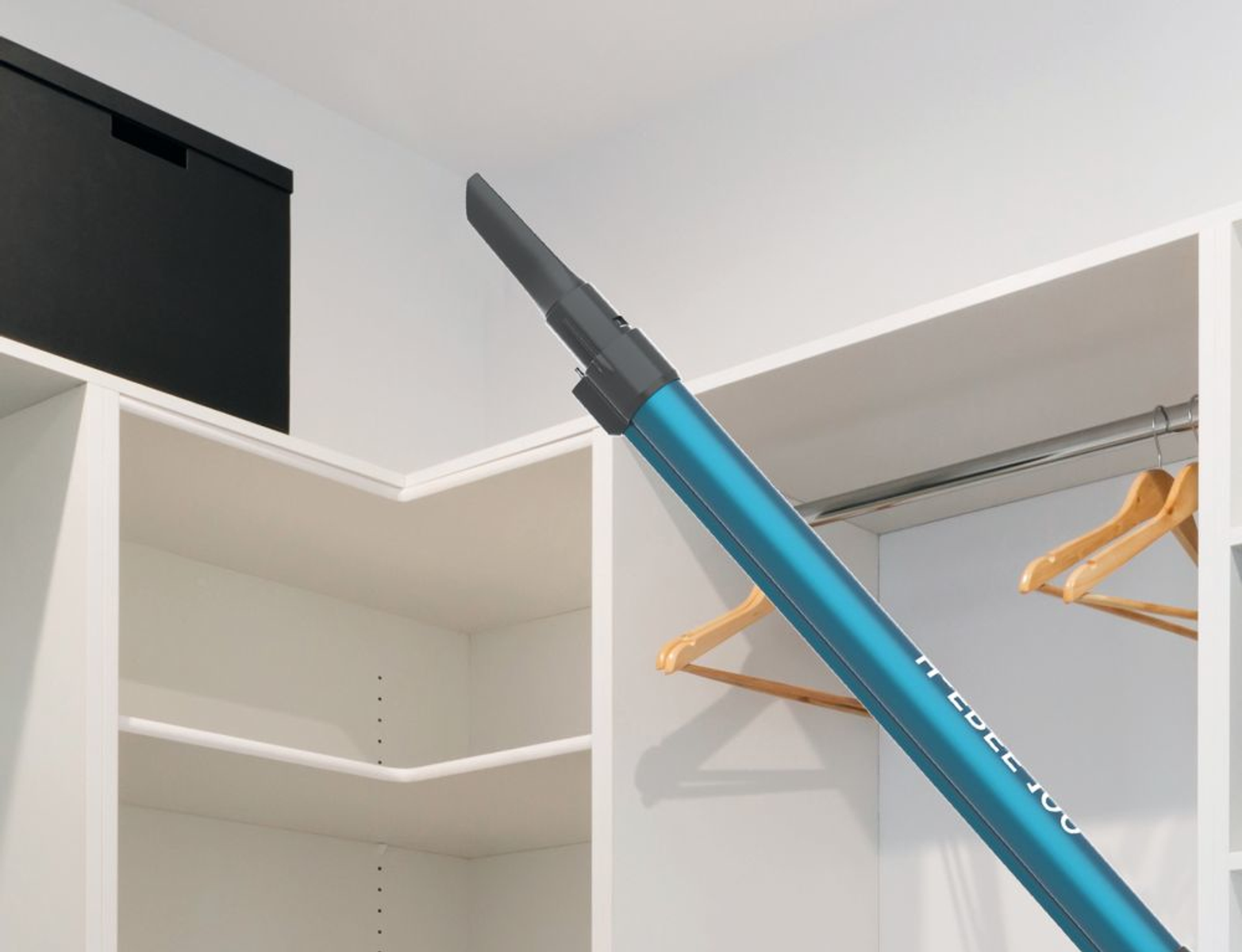 Ein blauer Staubsaugeraufsatz, der auf einen weißen Schrank mit Kleiderbügeln zeigt.
