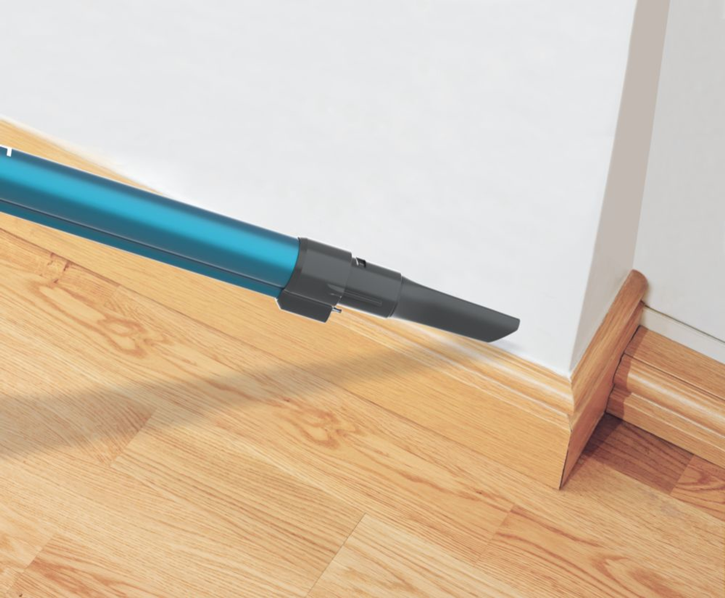 Staubsaugerdüse reinigt Wandecke. Holzboden und weiße Wand.